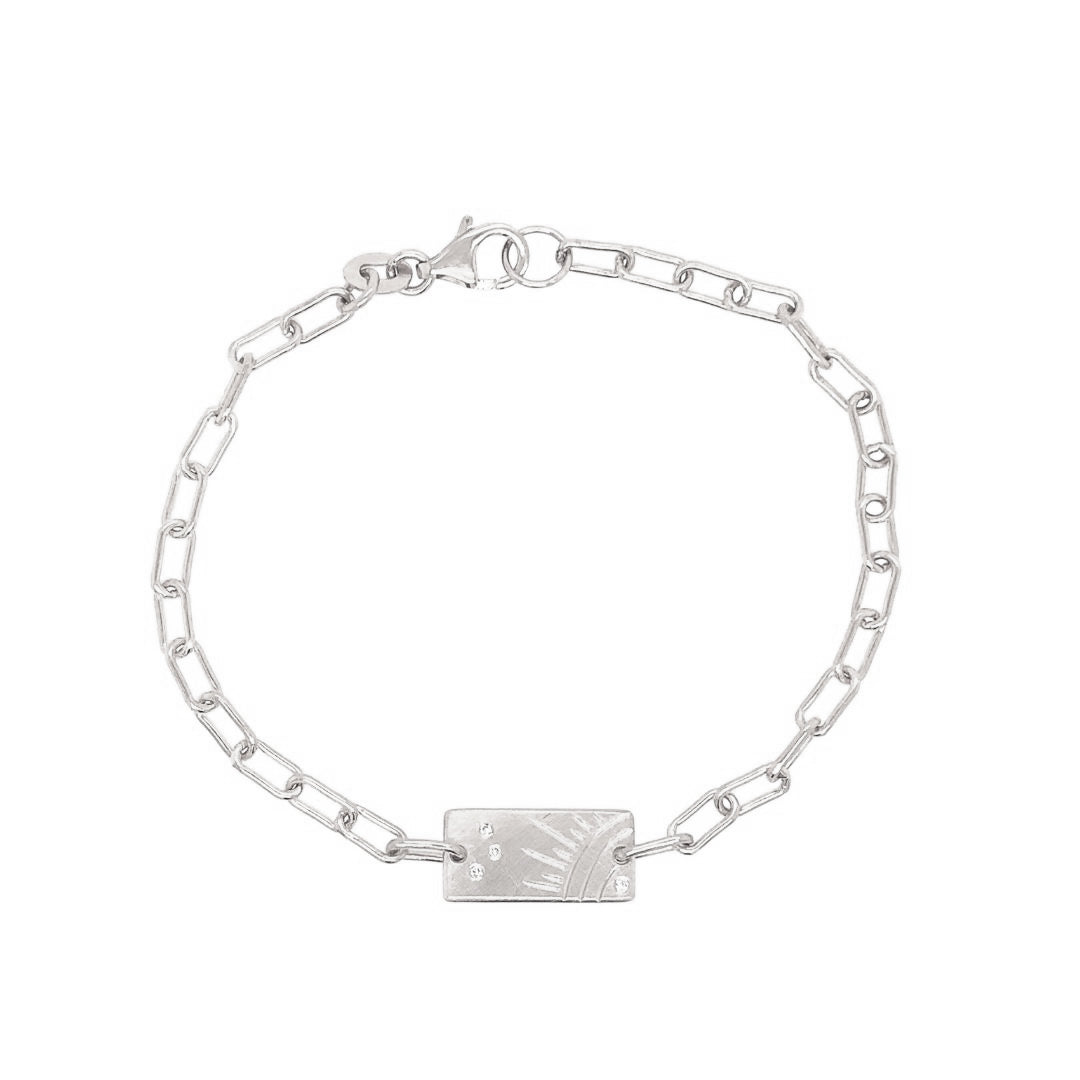 14k white gold paperclip link bracelet with rectangular charm featuring a hand etched sunburst and white diamond accents on a white background
