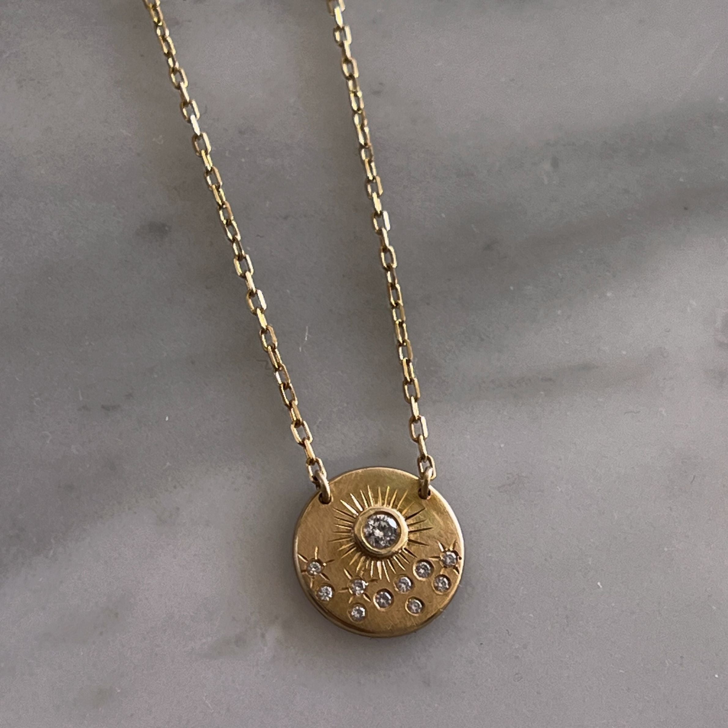 Celestial Star Necklace wit h 4k Gold and diamonds on a marble background