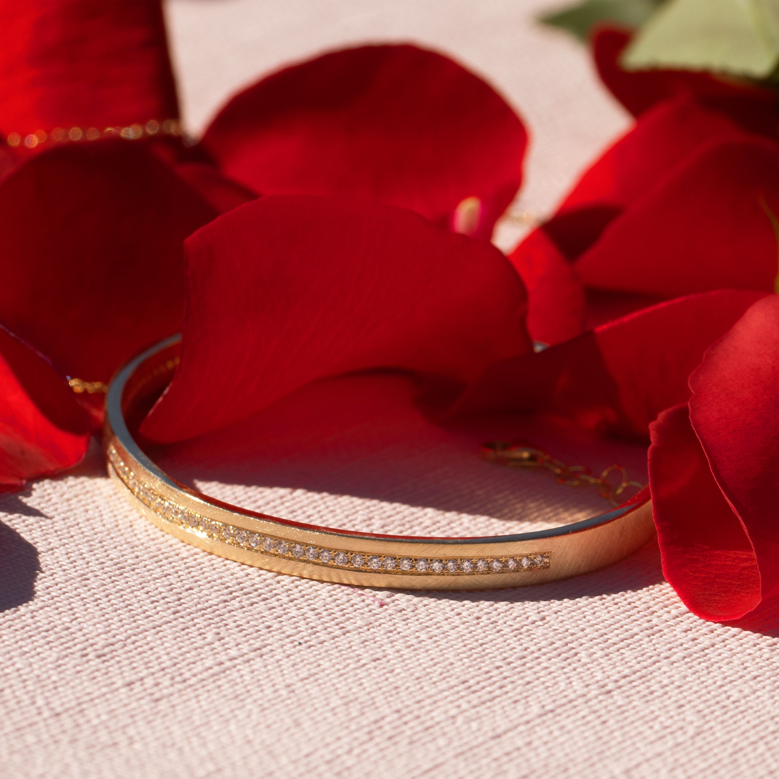 14k yellow gold pave set white diamond cuff bracelet with an adjustable chain on rose and gauze background