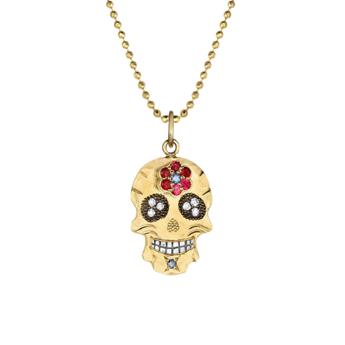 Gold skull handcut pendant necklace on a white background. Raised bezel set multi color gemstone flower on forehead. Blackened eyes with white diamonds. Shiny silver rhodium plating on teeth