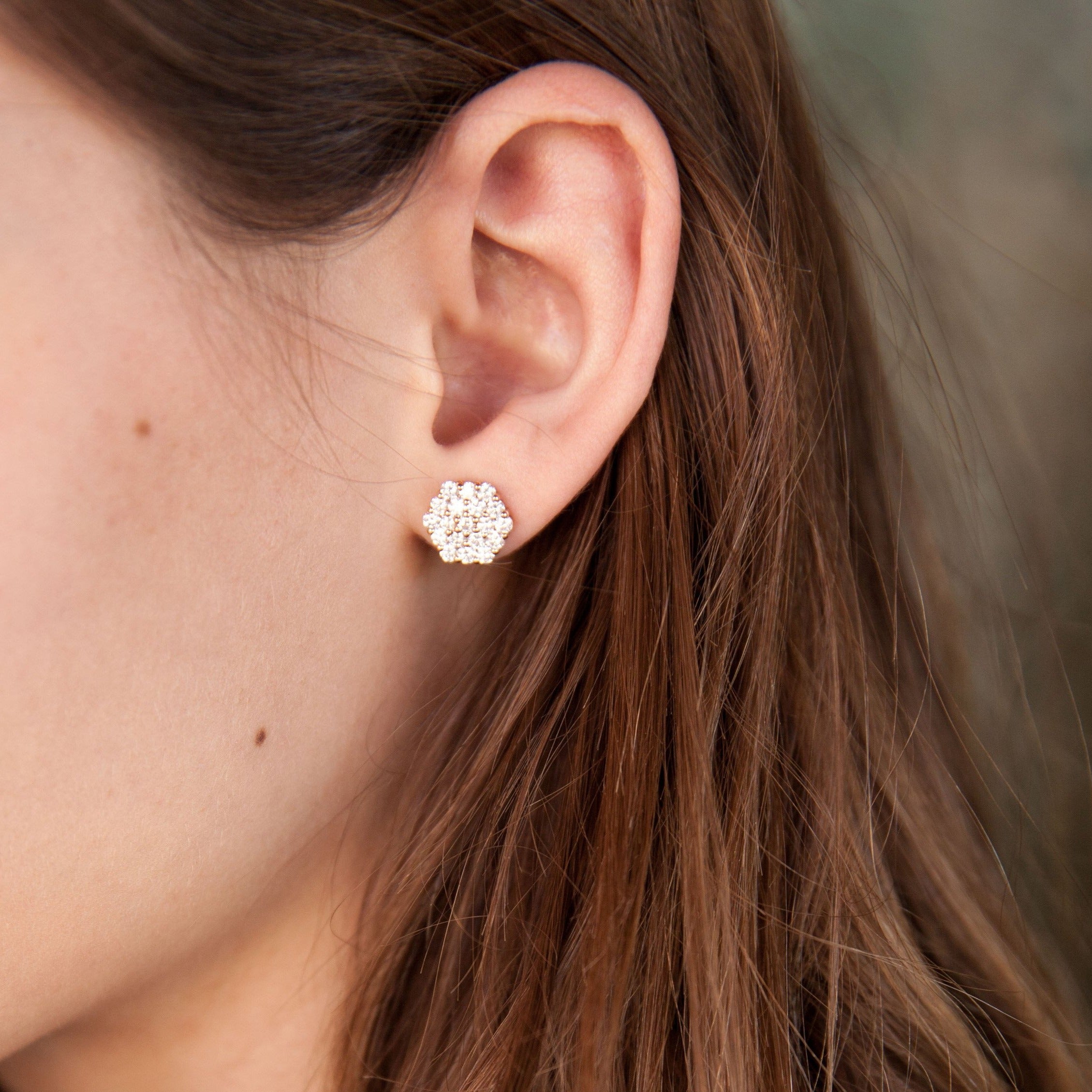 Close up model wearing  yellow gold post earrings cluster set white diamonds geometric earrings blurred background