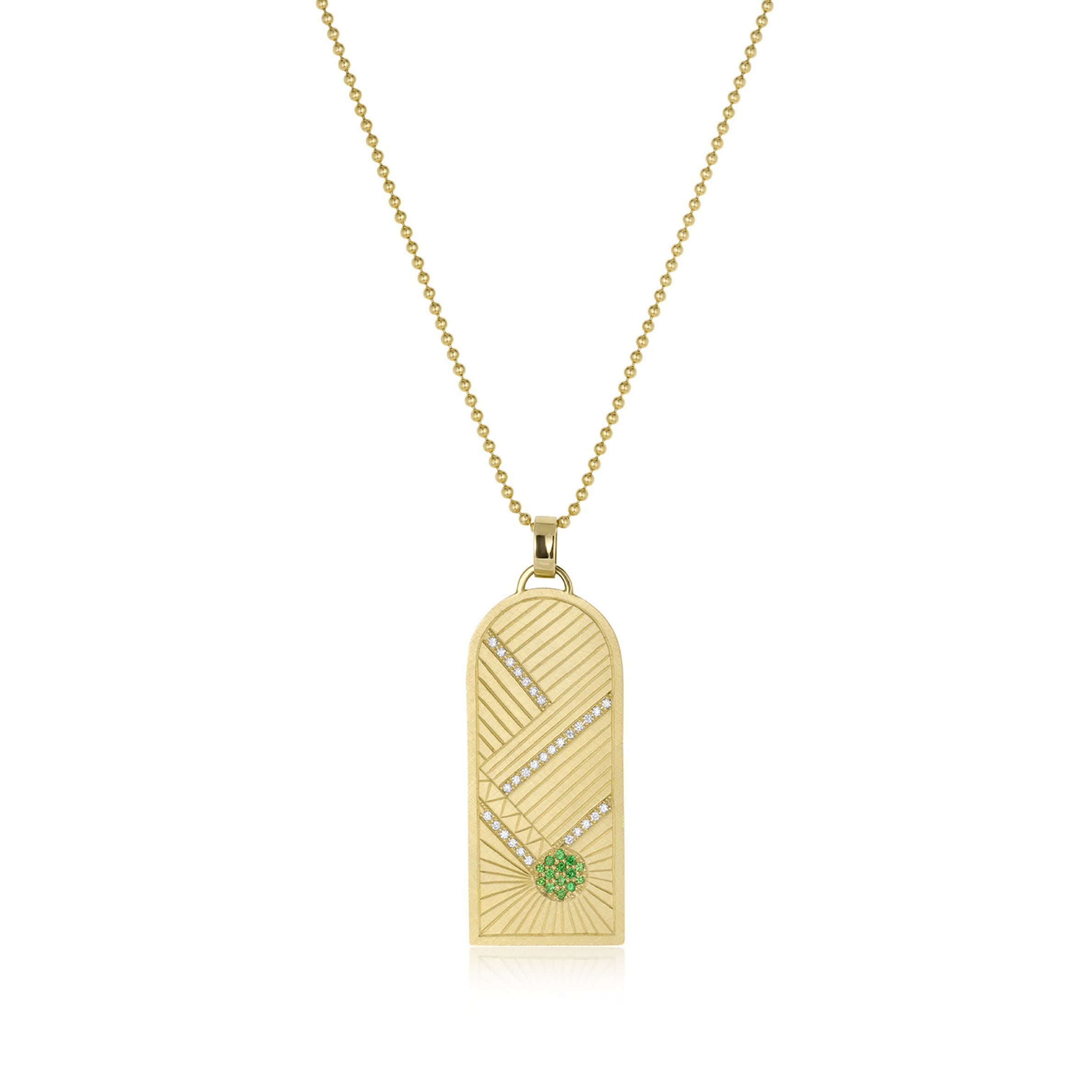 14k yellow gold pendant featuring hand etching with green gemstone sunburst and white diamonds on a ball chain on white background