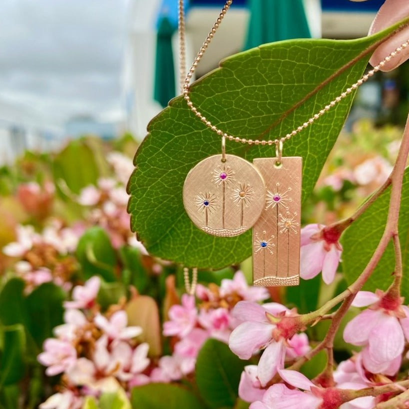 14k yellow gold round and rectangular pendants with floral sapphire etching on diamond cut ball chain on a natural background