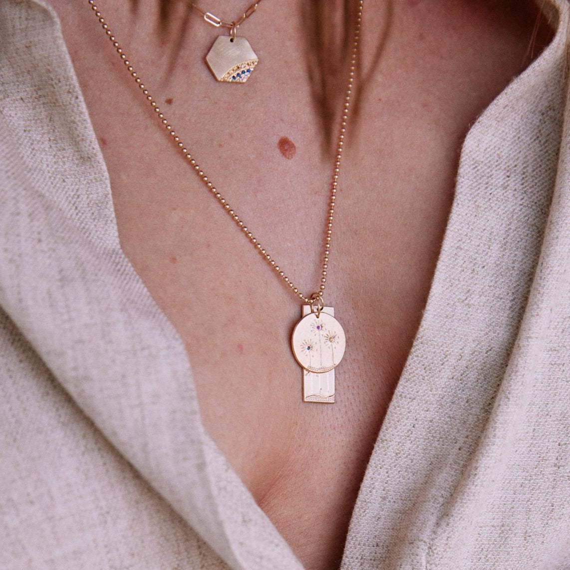 14k yellow gold round and rectangular pendants with floral sapphire etching on  ball chain on lifestyle shot on model
