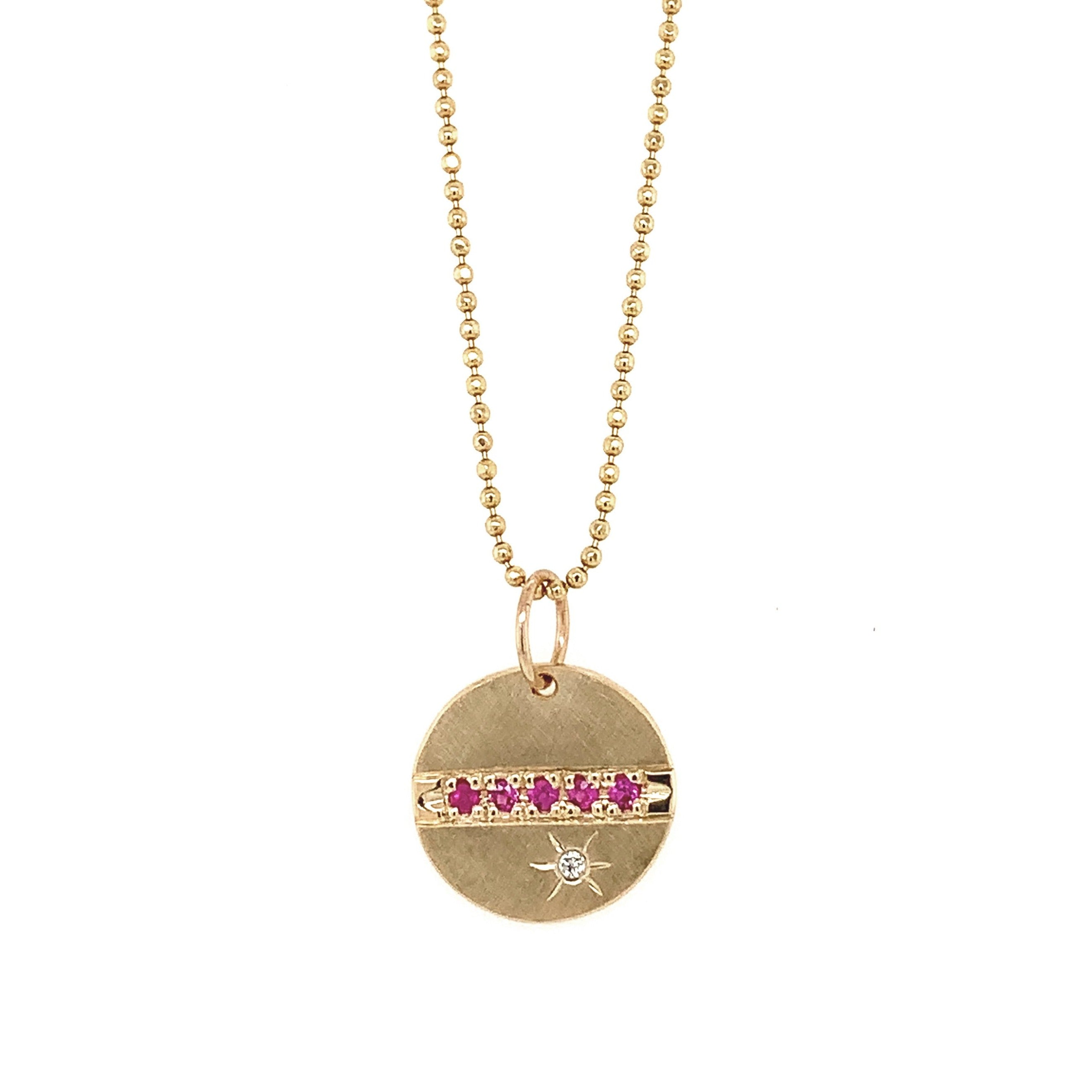 14k yellow gold round pendant featuring pink sapphires and a white diamond sunburst on diamond cut ball chain on a white background