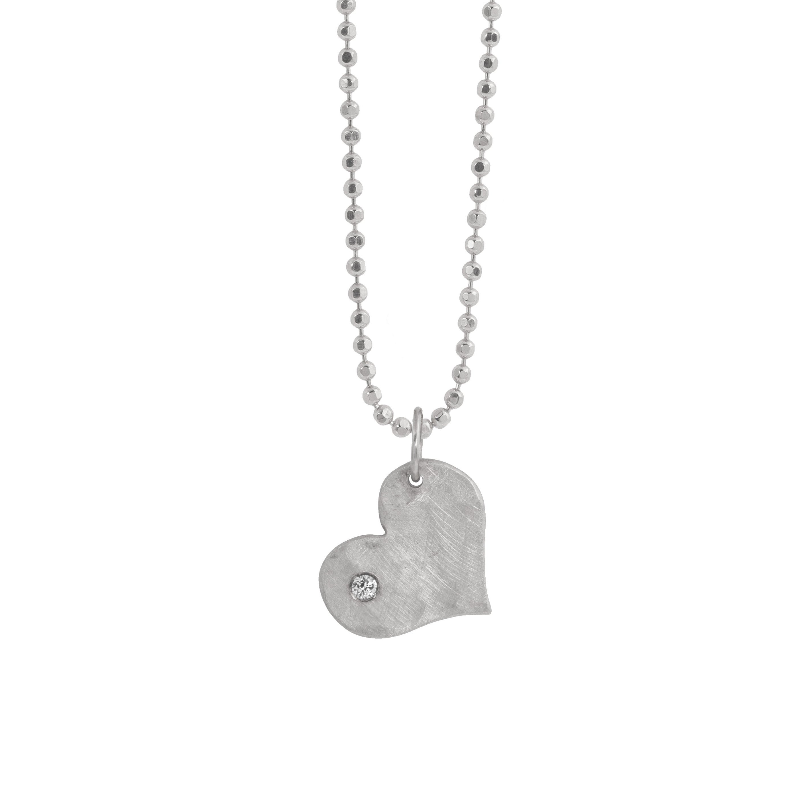 14k white gold heart-shaped pendant with an offset white diamond on diamond cut ball chain on a white background