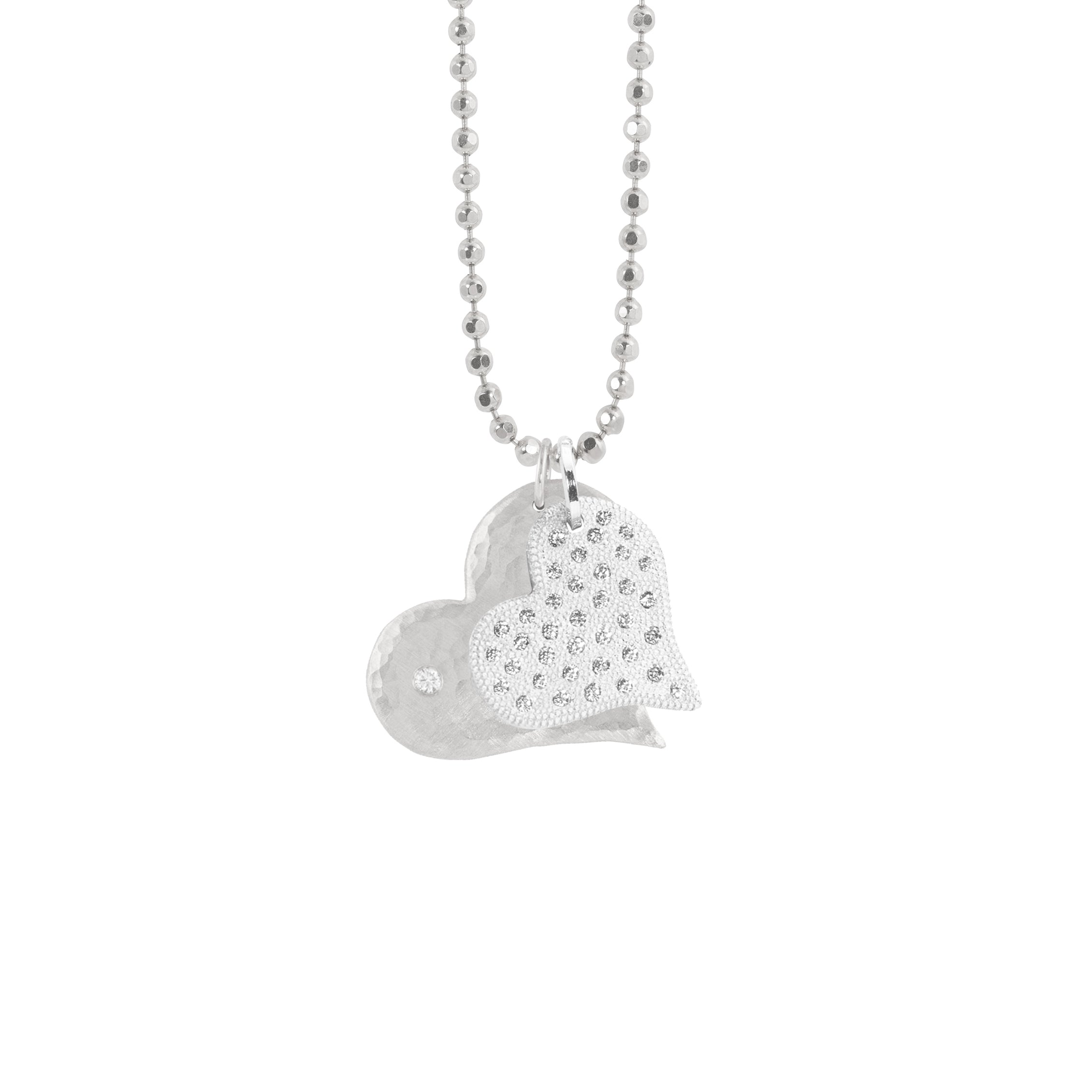 14k heart pendants featuring the lana in white gold with a hammered finish and white diamond and the lava in white gold with beaded textures and scattered white diamonds on diamond cut ball chain on white background