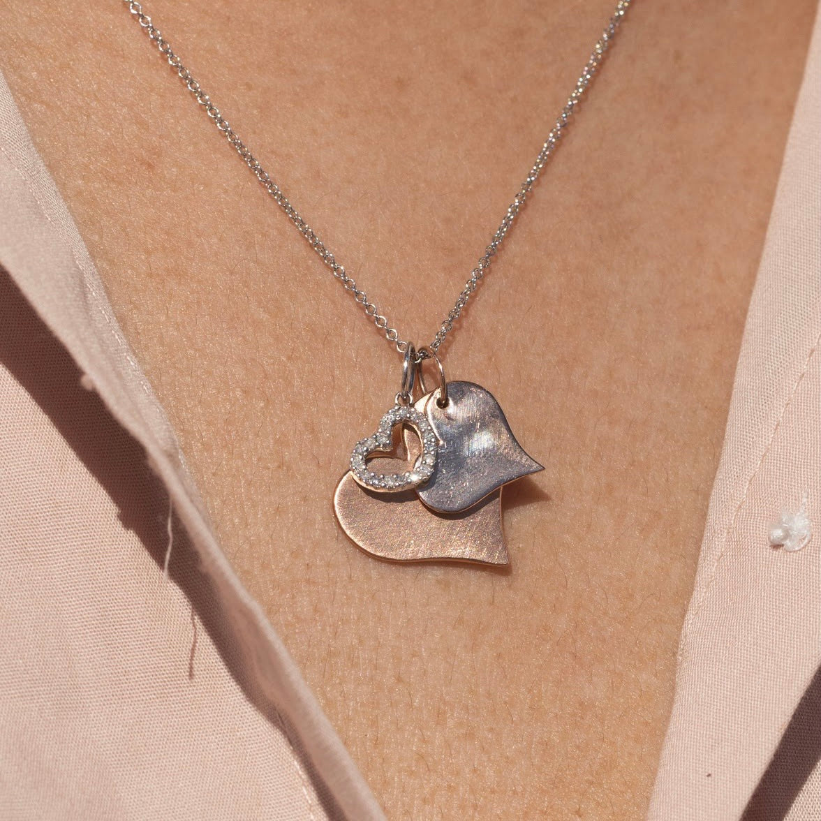 14k white gold open heart-shaped pendant on a rolo chain stacked with two heart shaped pendants on model in lifestyle shot