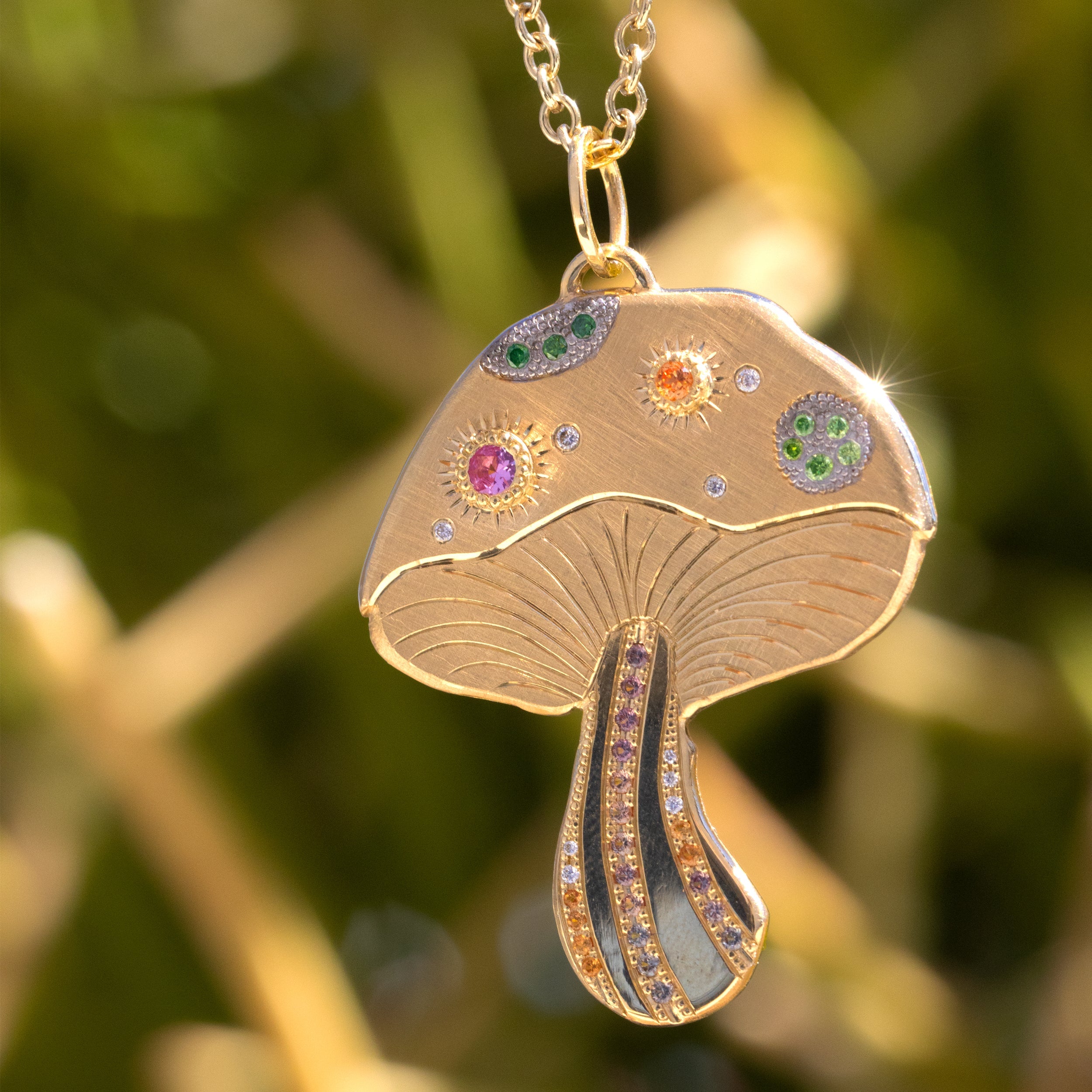 14k yellow gold extra large mushroom pendant with colored gemstones and white diamonds with hand etched details on rolo chain on nature background