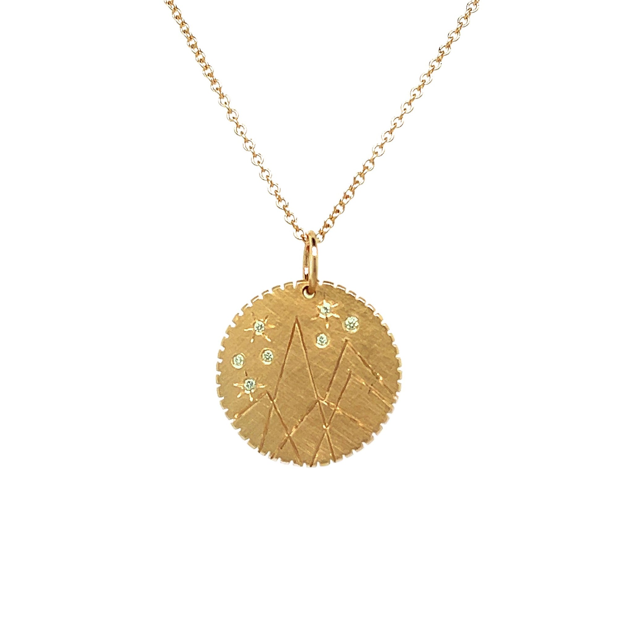 14k gold round pendant with mountains etching and white diamond details.