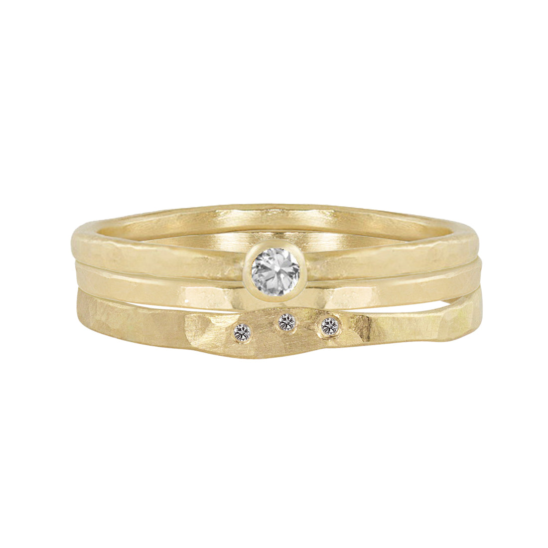 14k yellow gold hammered stackable ring with three white diamonds stacked with 14k yellow gold bezel set white diamond ring and 14k yellow gold hammered band on a white background