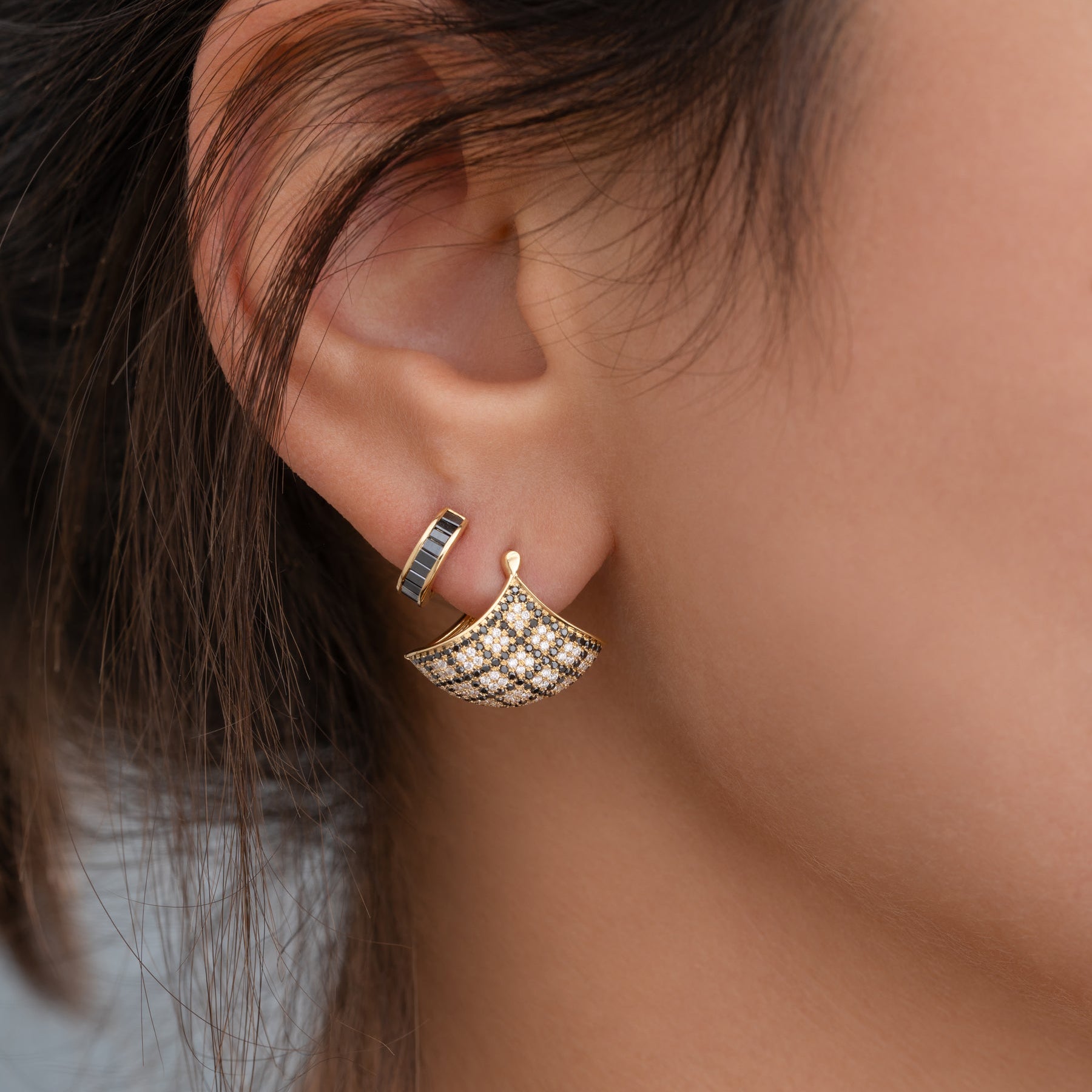 Close-up of a gold earring worn on an ear with a blurred background