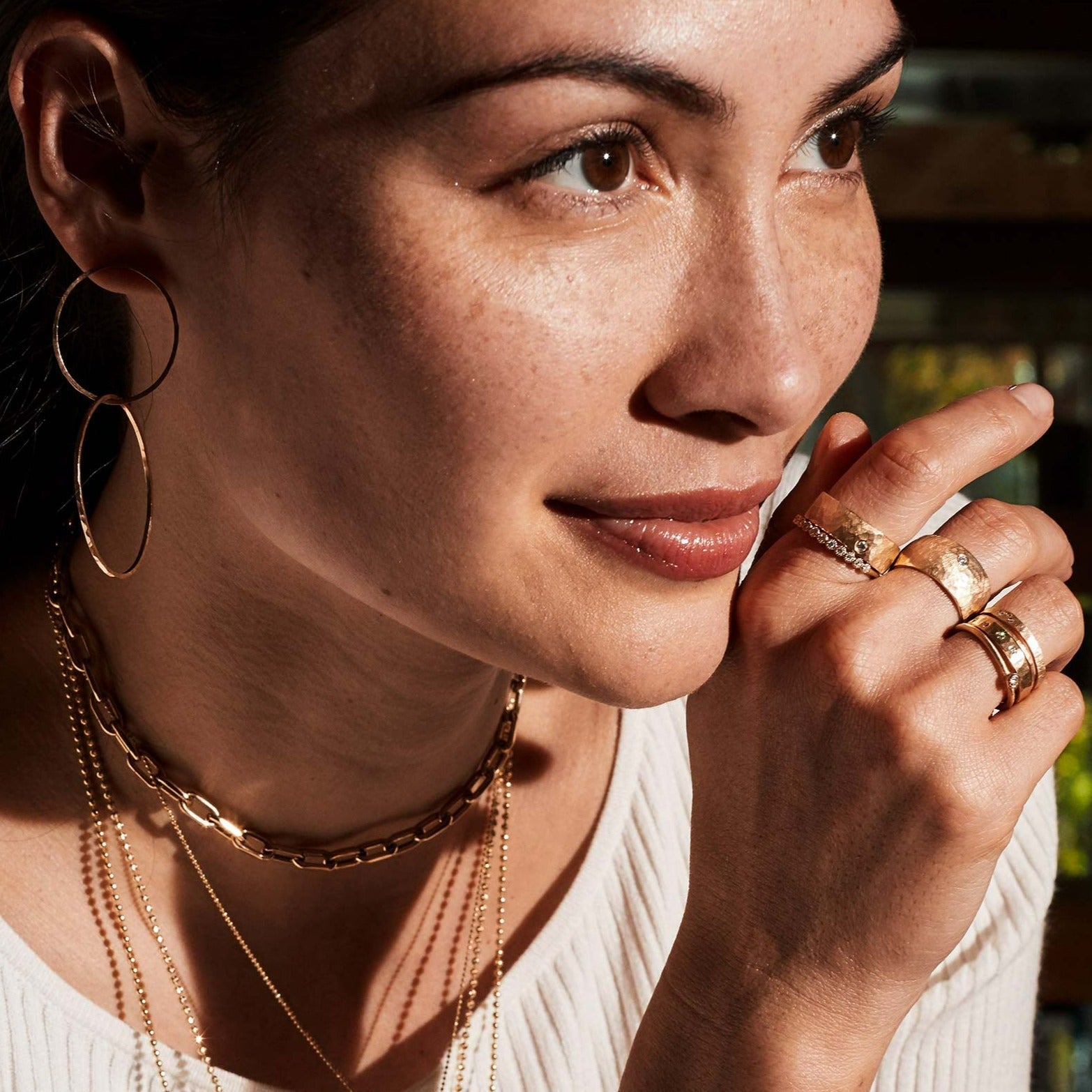 14k yellow gold hammered wide refe band with single diamond accent on model in lifestyle shot paired with other rings by julez bryant