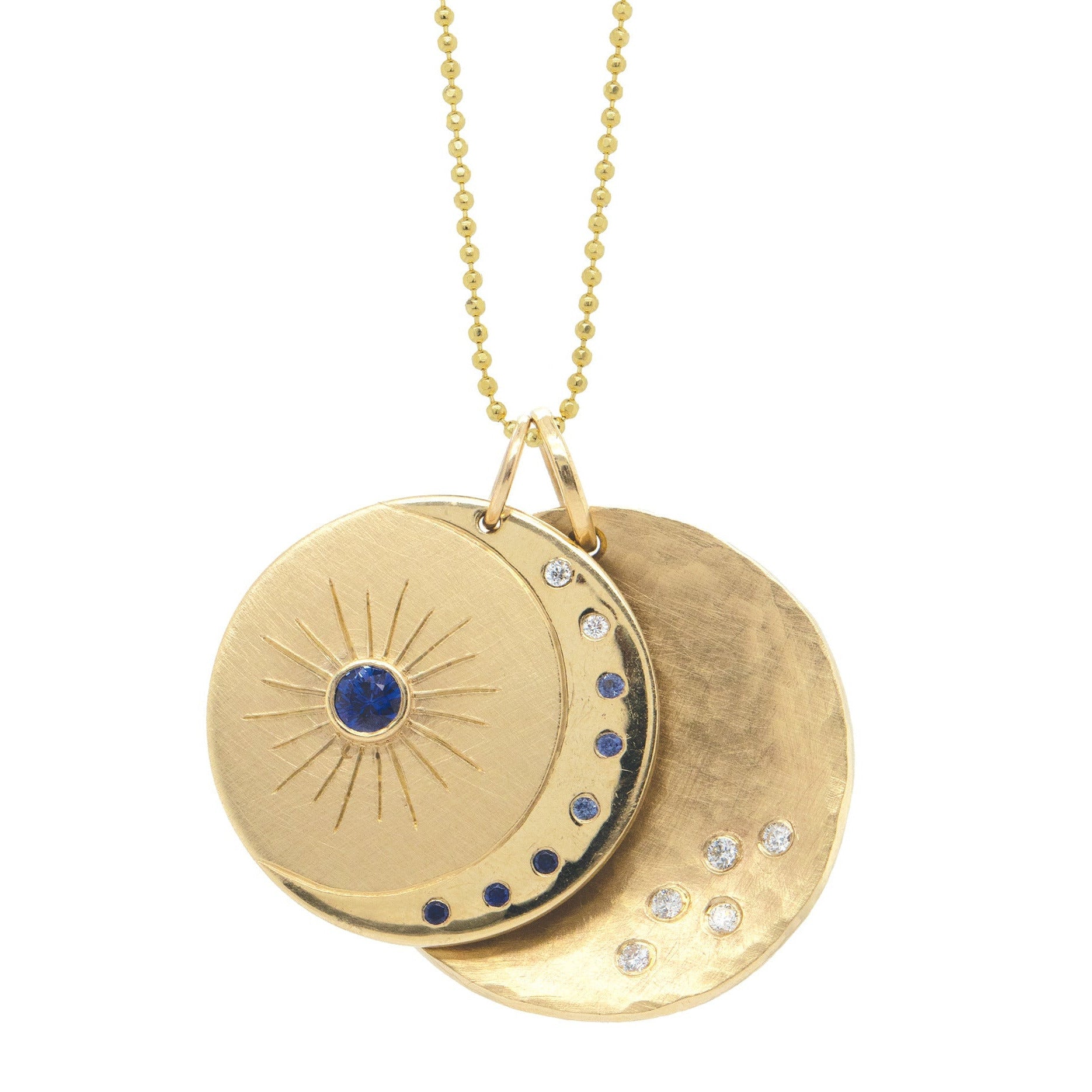Yellow gold necklace with two circular pendants celestial design featuring white diamonds and sapphires moon and stars on a white background