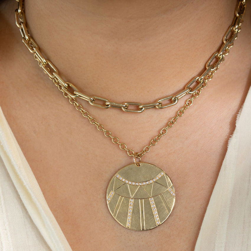 Model in white shirt wearing chunkygold choker and round link chian with extra large diamond disk medallion necklaces