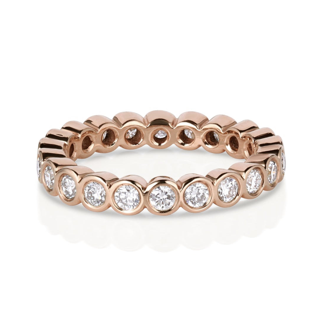 14k rose gold bezel set white diamond eternity band on white background