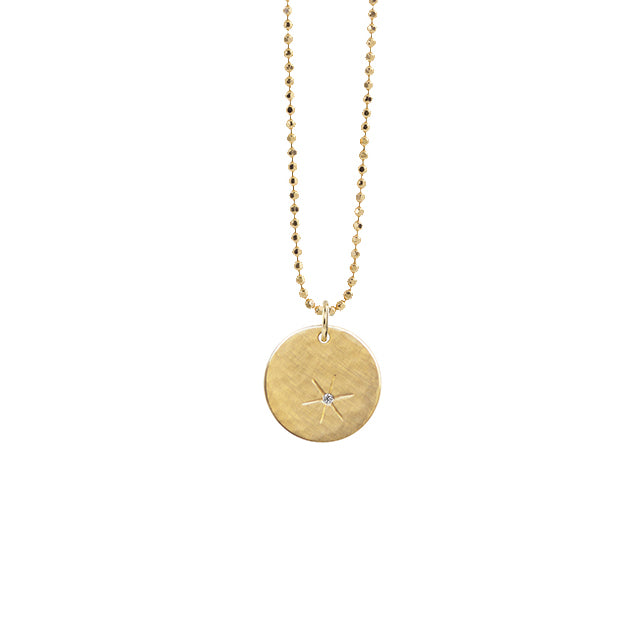 14k yellow gold round pendant with hand etched starburst with white diamond on diamond cut ball chain on a white background