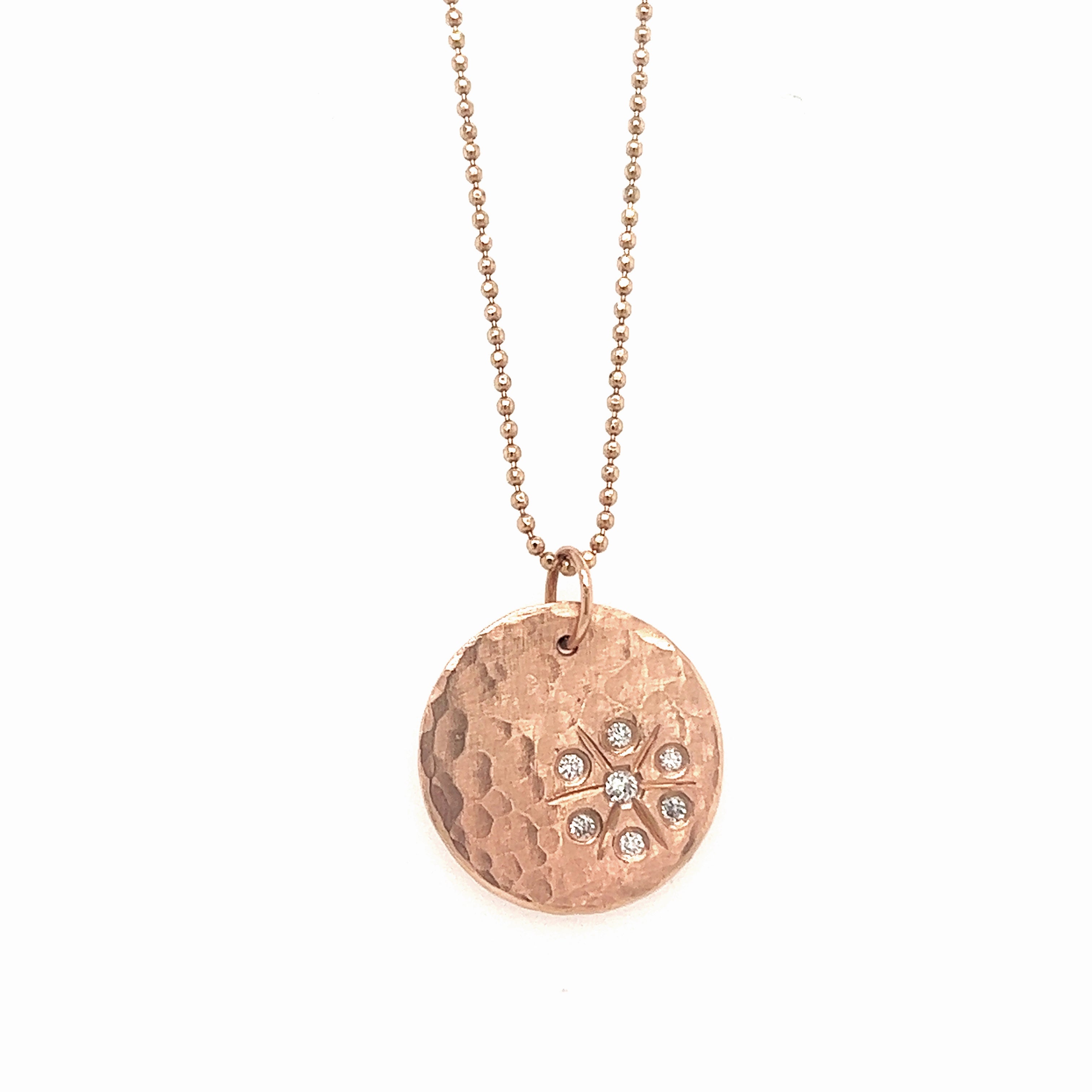 14k rose gold round hammered pendant with white diamond starburst on a white background