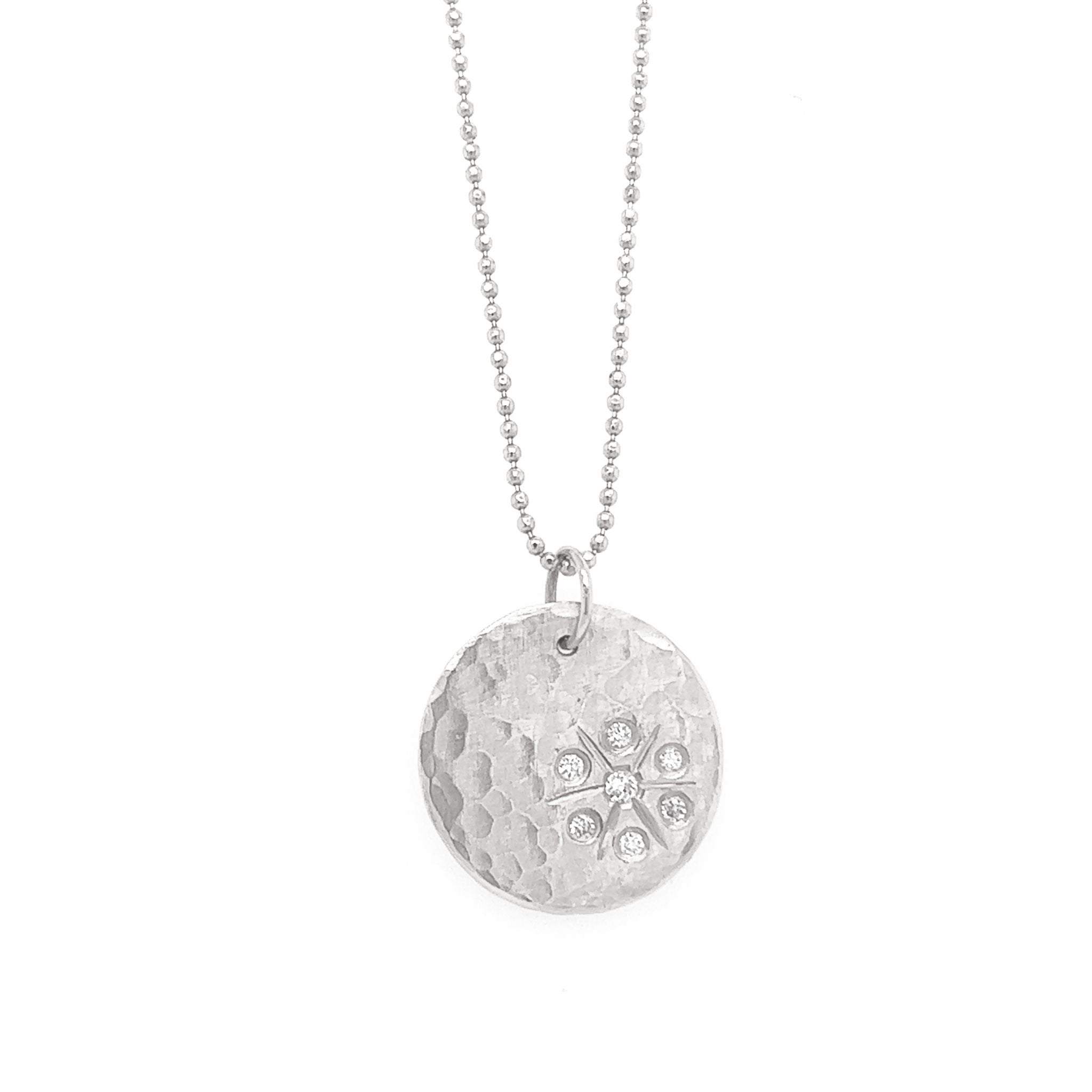 14k white gold round hammered pendant with white diamond starburst on a white background