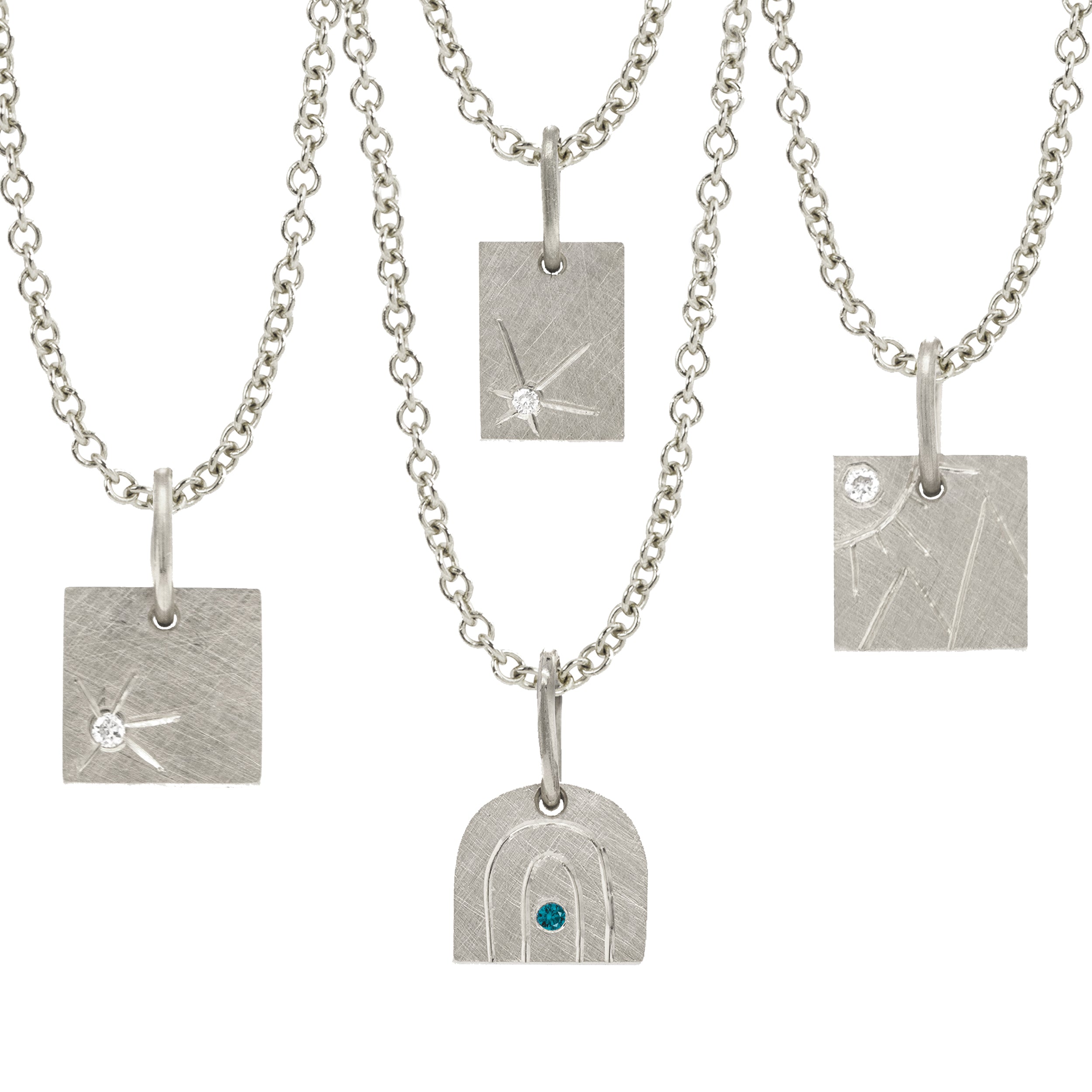 14k white gold square pendant with hand etched mountains and sun with white diamond paired with other square pendants featuring hand etched sunbursts with white diamonds and a rainbow pendant with a teal diamond on a white background