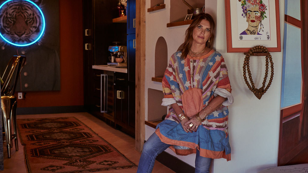 Woman in a colorful poncho sitting in a room with artistic decor