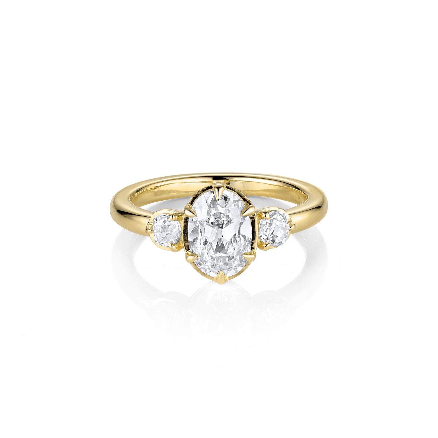 3 stone yellow gold ring with a central large oval diamond and smaller round diamonds on the sides against a white background