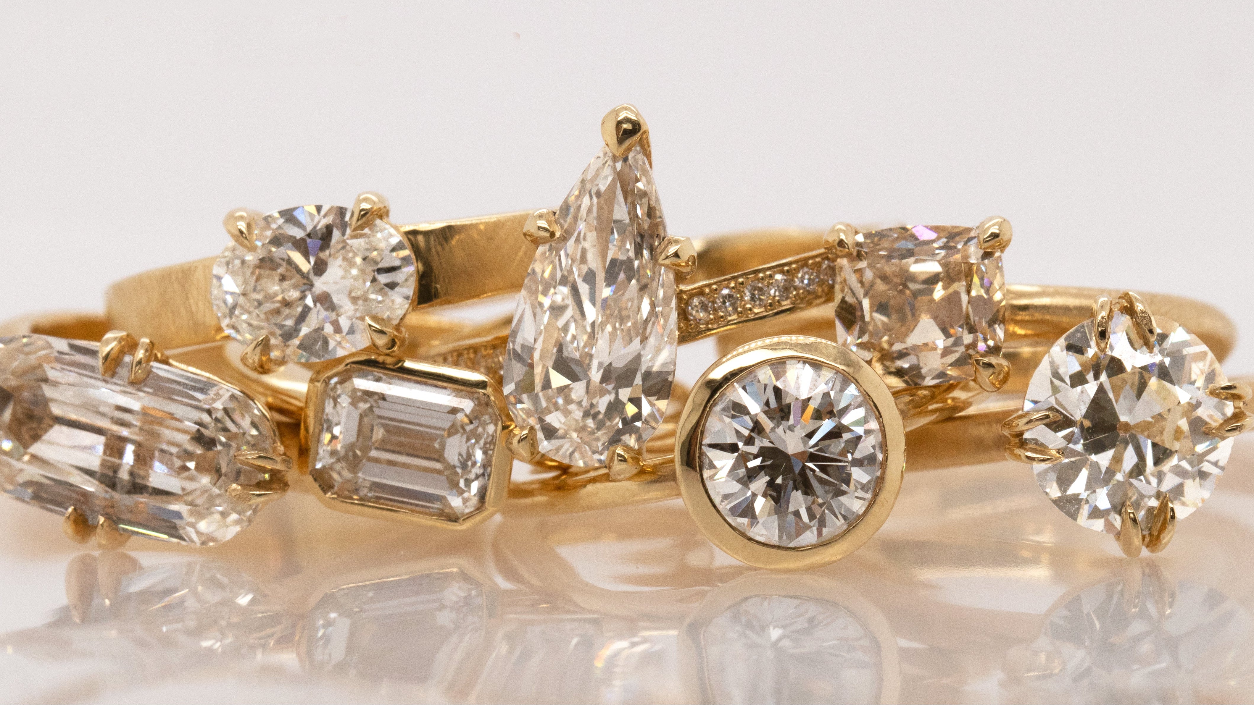 Gold ring with multiple diamonds on a reflective surface, featuring the brand 'Julez Bryant'.