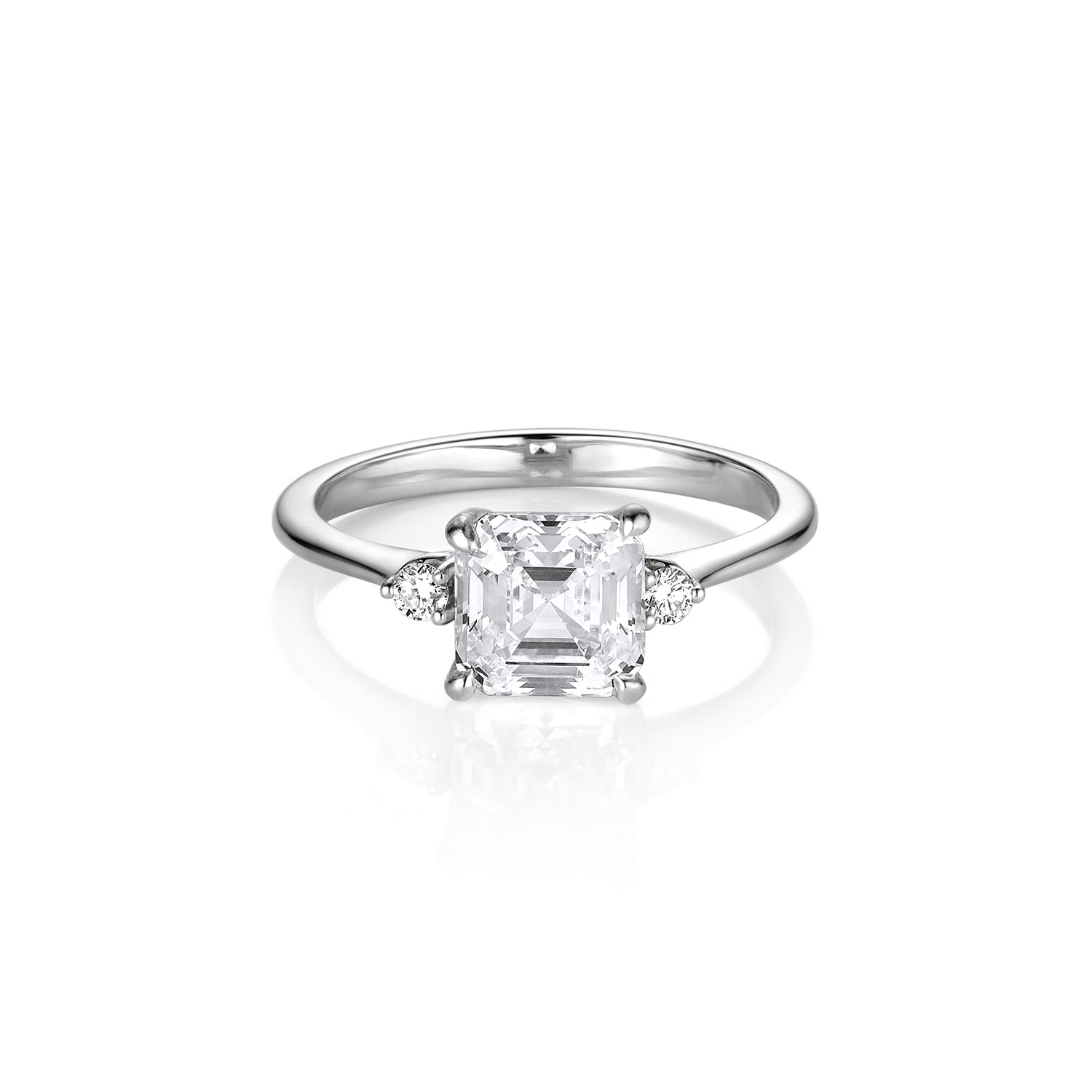 Three stone emerald and round cut white gold engagement ring thin band high polish on white background