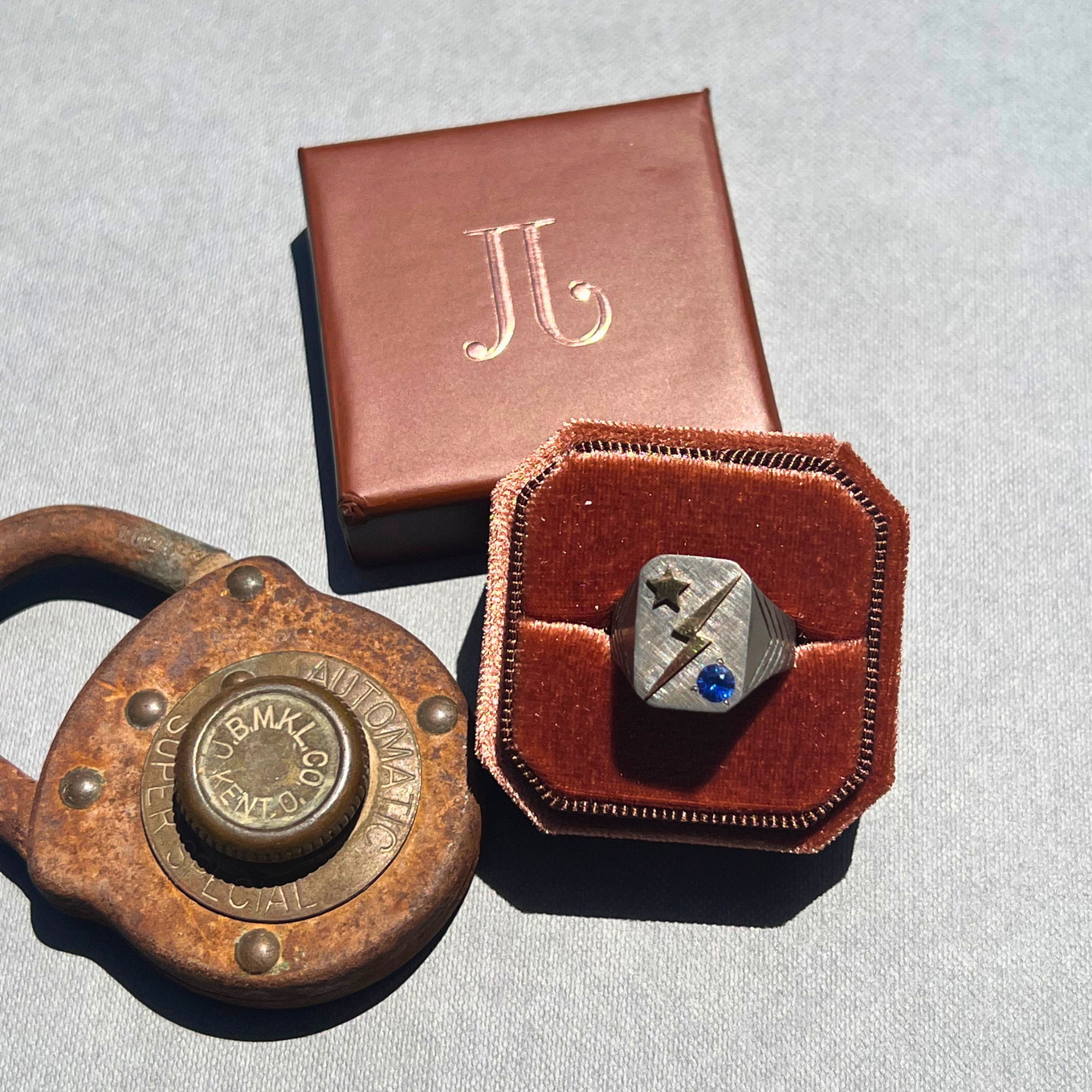 Image of a celestial signet chunky sapphire sterling silver with 14k yellow gold accent ring in rust colored velvet box.