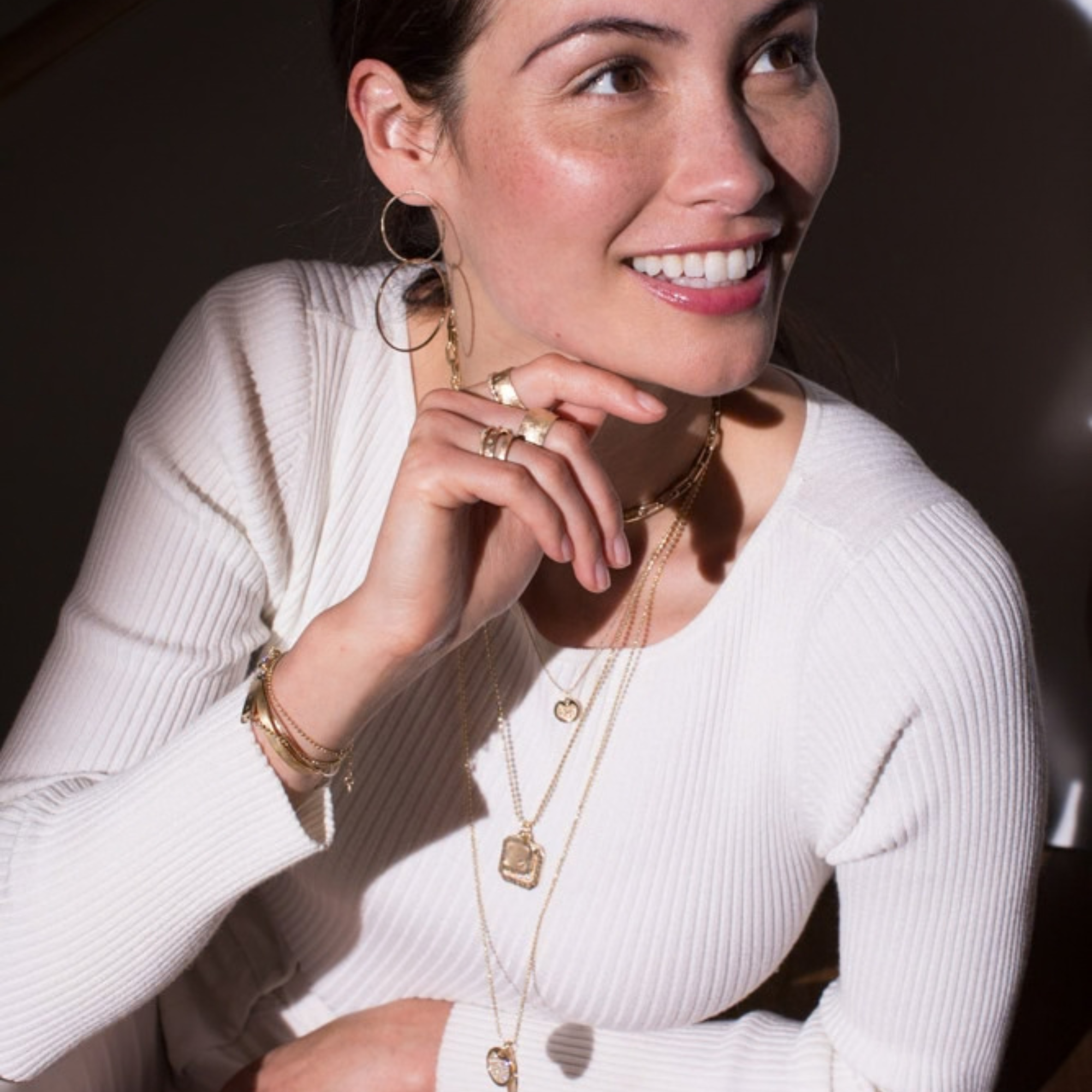 14k yellow gold round pendant with milgrain texture and scattered white diamonds stacked with two square pendants with white diamond details on model in lifestyle shot