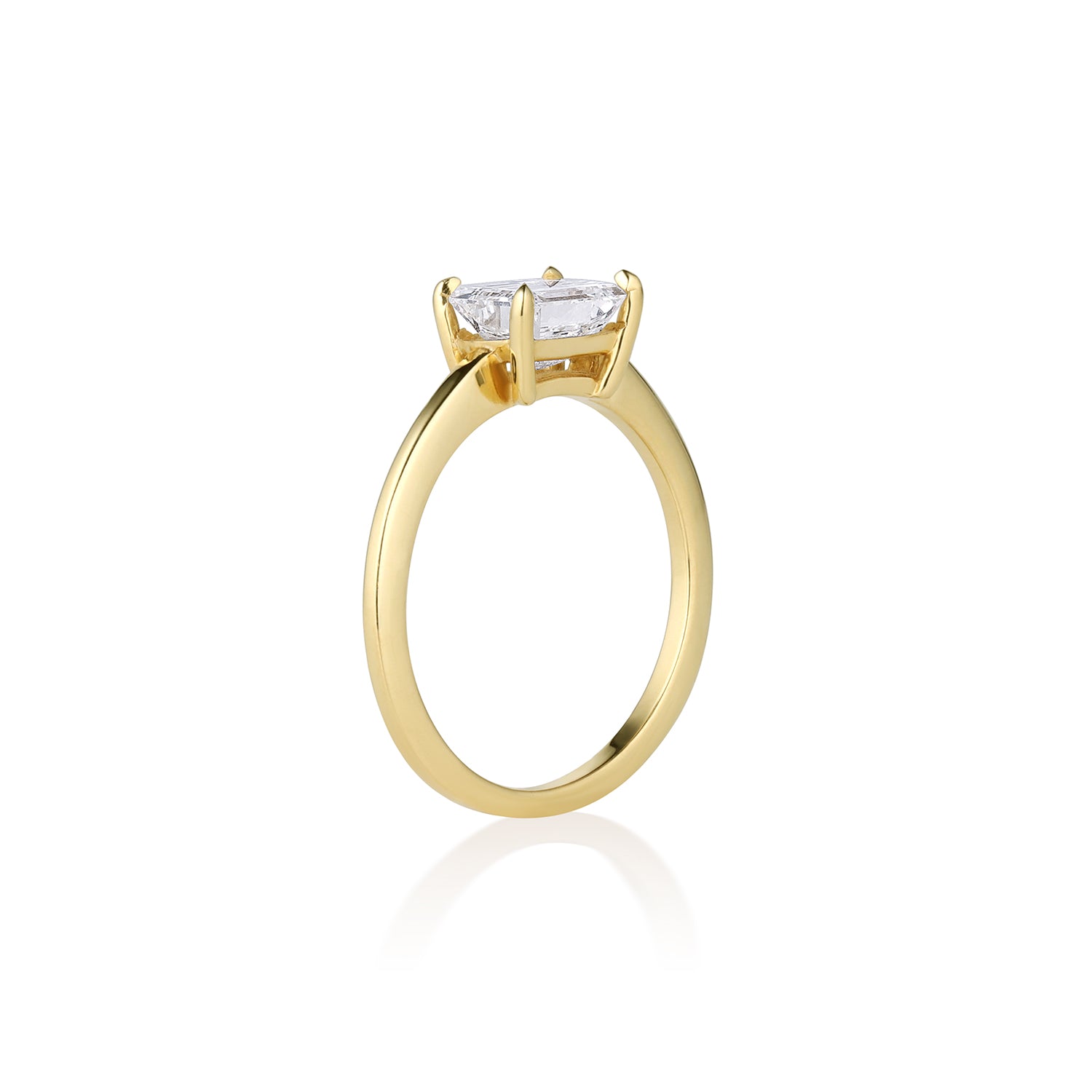 Side view of emerald cut solitaire engagement ring. Prong setting shiny finish. Shown on white background.