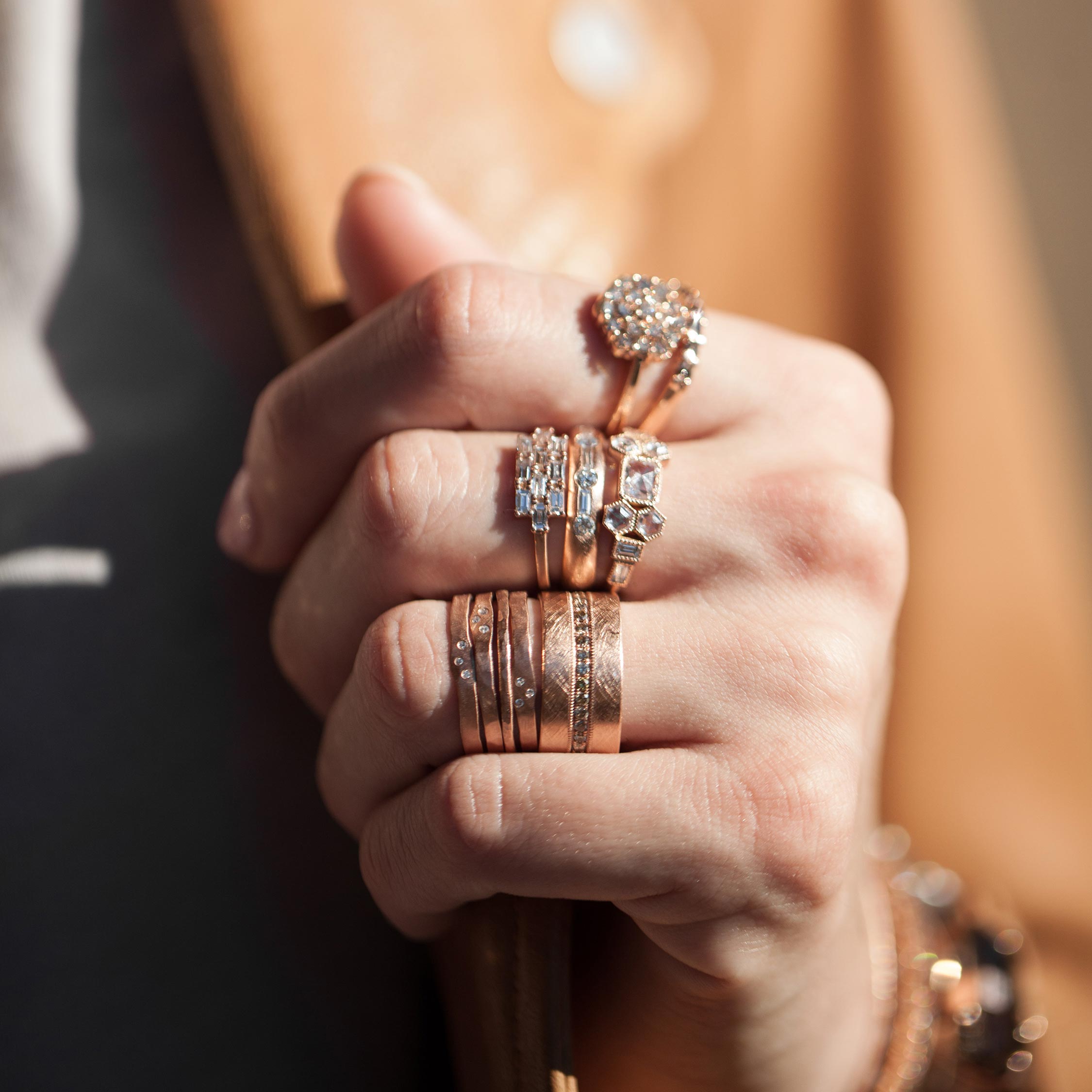 Hand wearing multiple rose gold rings with a blurred background