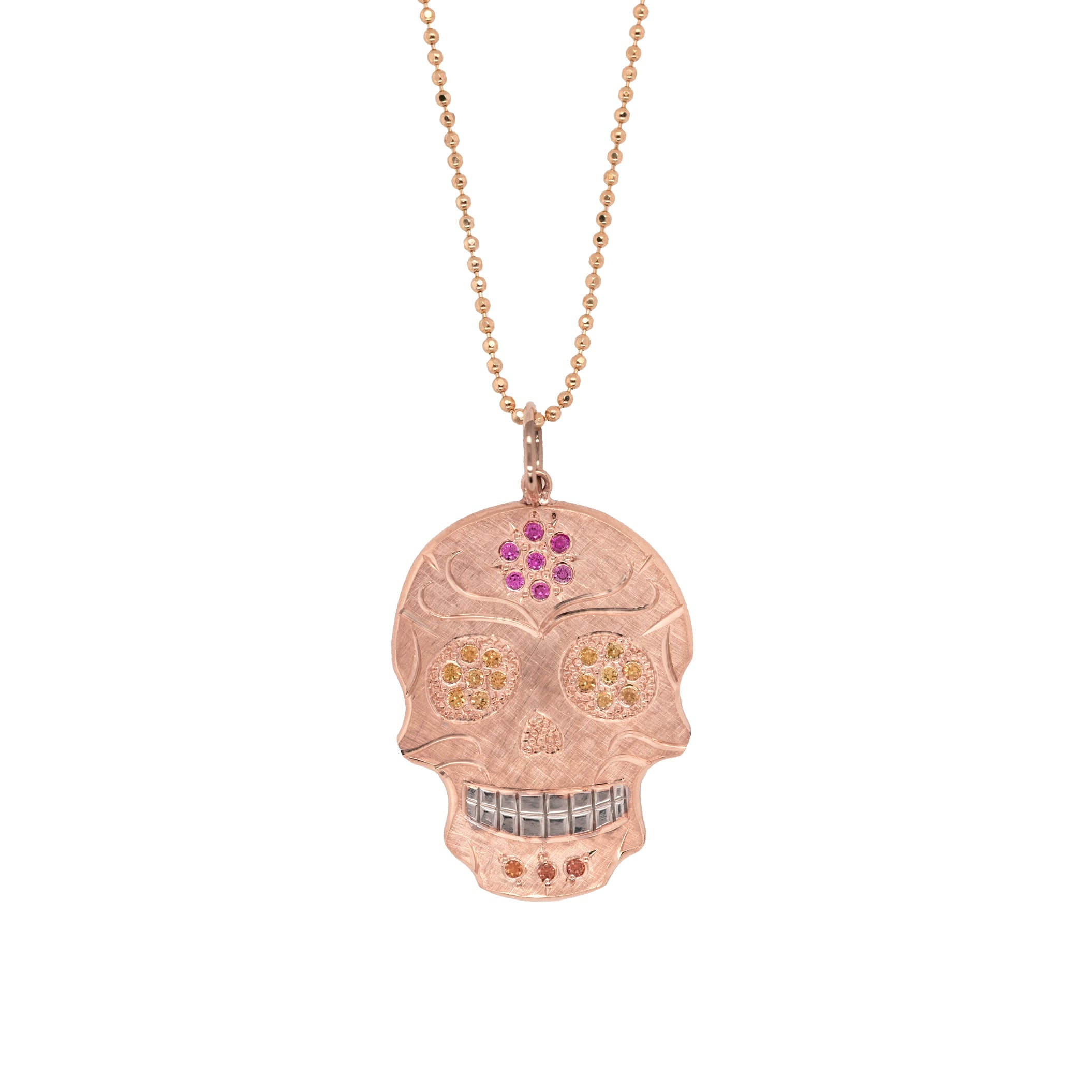 14k rose gold handcut sugar skull pendant with gemstone details hand engraving and rhodium brightened teeth shown on chain on white background