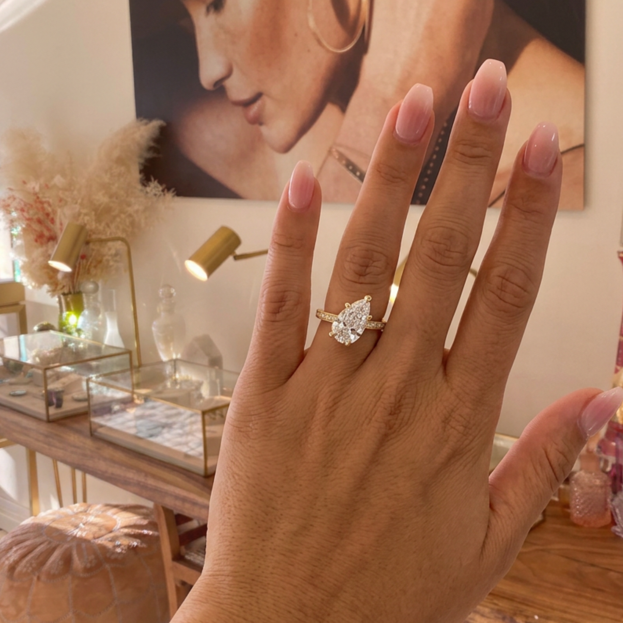 Image of a lab grown tilted pear cut cut solitaire pavé diamond engagement ring in 14k yellow gold on lifestyle shot worn on a model.