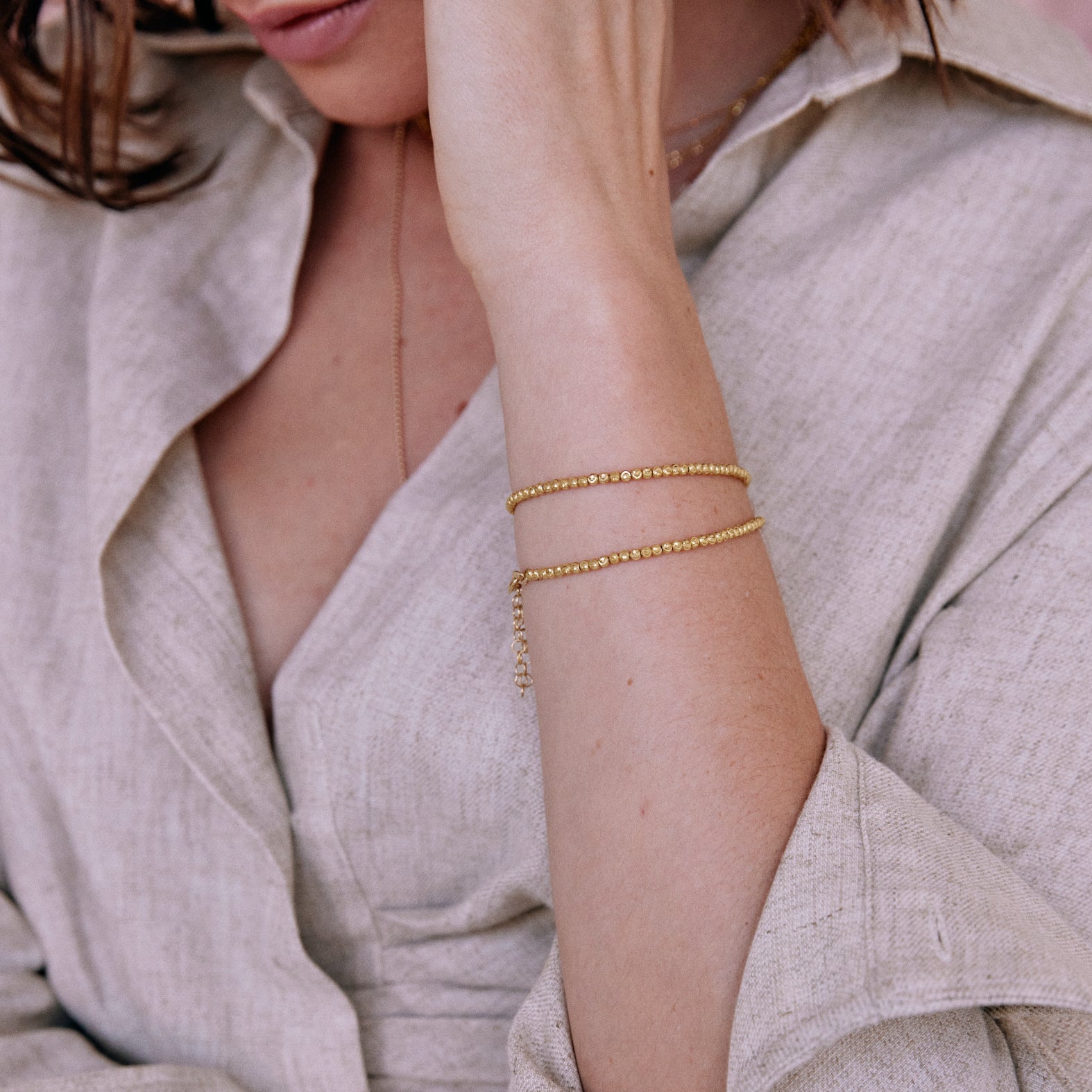 Close up of person wearing gold double wrap faceted bead bracelet blurred background