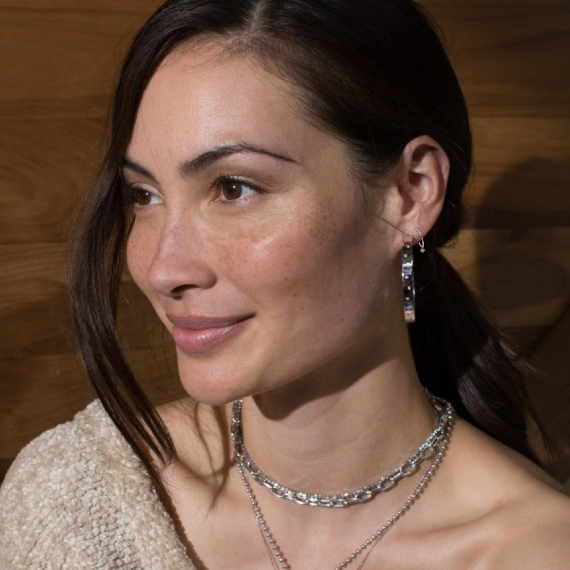 14k white gold hoop earrings with bezel set white diamond charms next to larger hoop on model in lifestyle shot