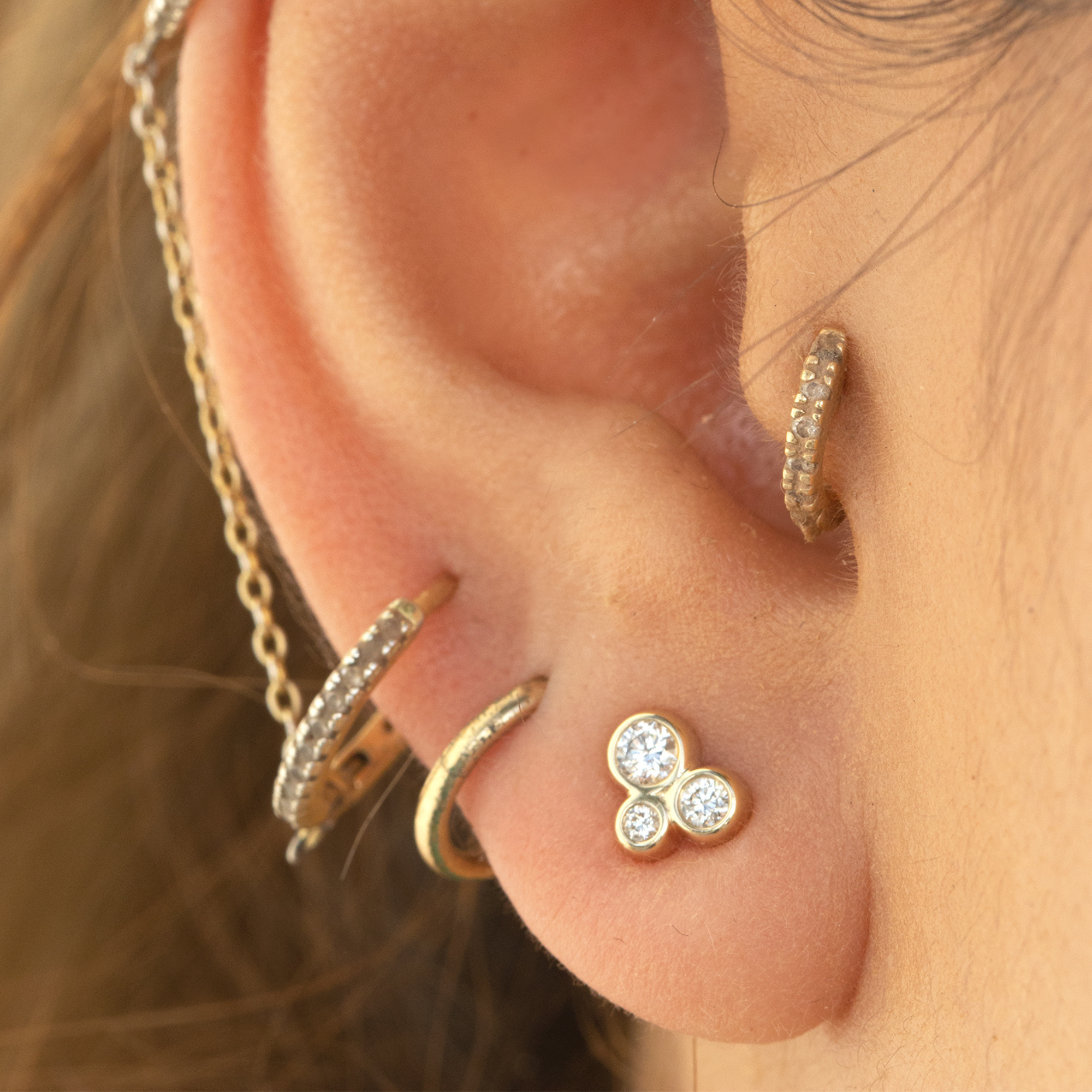 14k yellow gold triple diamond bezel stud earrings on model in lifestyle shot