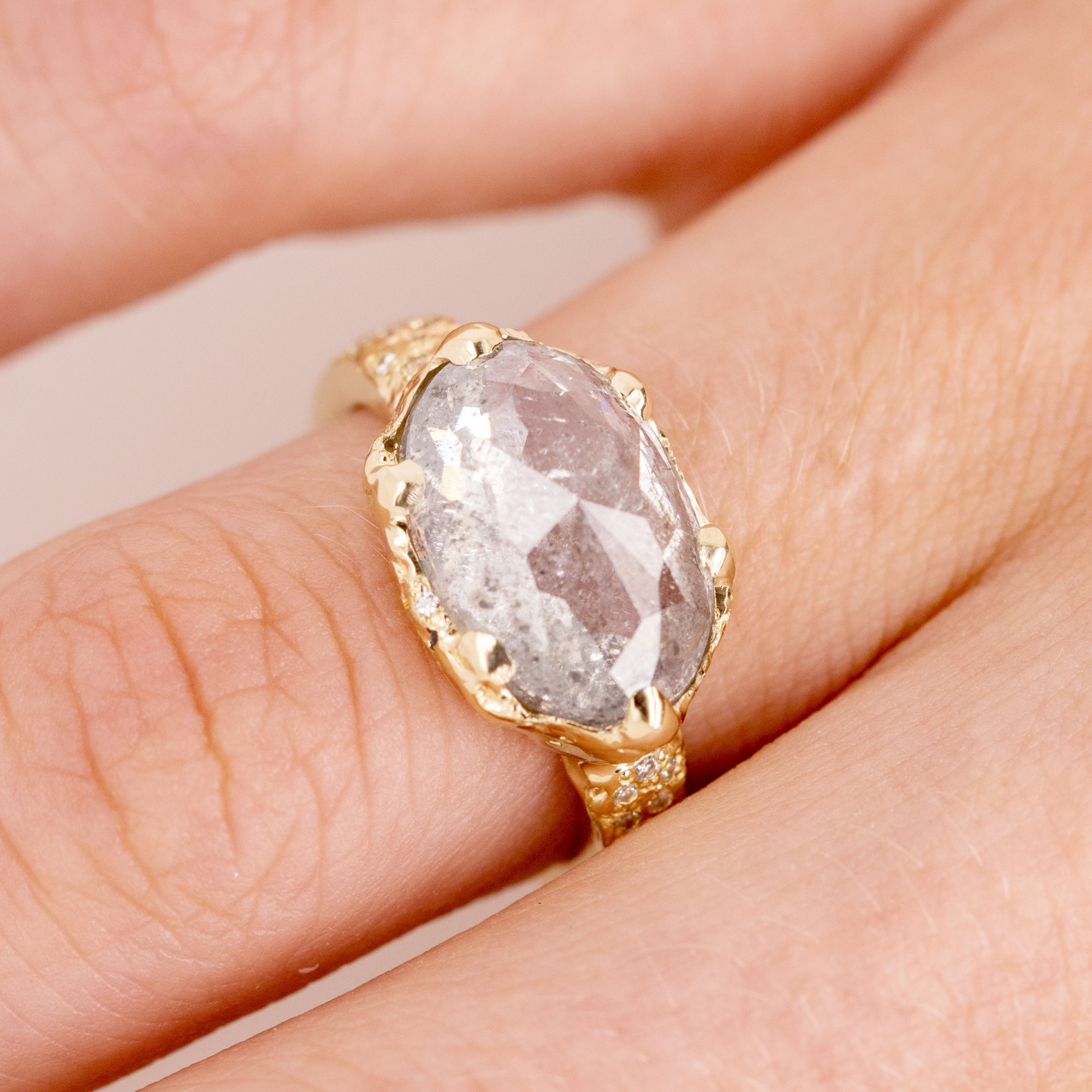 14k gold oval salt and pepper diamond with organic edge ring on hand in lifestyle shot