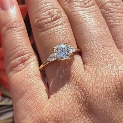 Candid video of three stone engagement ring in 14k yellow gold and lab-created diamonds featured double claw prongs and trillion accents in pink worn on hand.