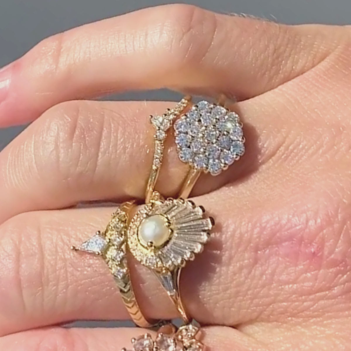 Candid video of hexagon shaped diamond cluster engagement ring stacked with complimenting bands shown close-up on hand.