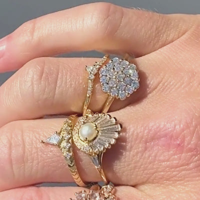 Candid video of hexagon shaped diamond cluster engagement ring stacked with complimenting bands shown close-up on hand.