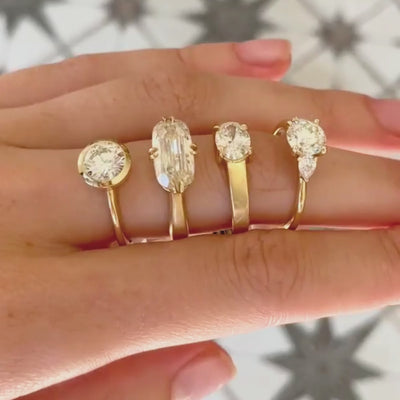 Candid close up video of hand wearing four different white diamond solitaire engagement rings with blurred background