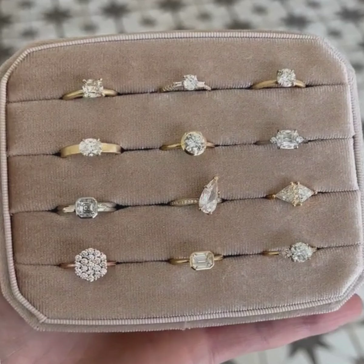 Candid video of assortment of unique solitaire engagement rings in14k yellow gold and lab-created diamonds in grey velvet ring display.