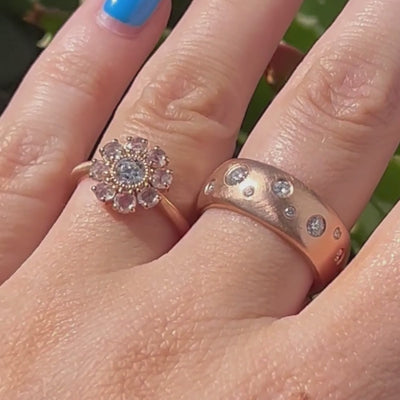 Candid video of hand wearing two rings in rose gold with diamond accents. Flower cluster engagement and wide band comfort fit wedding band.