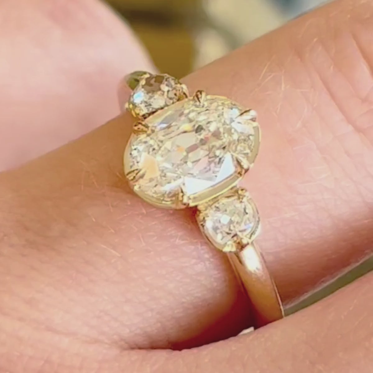 Candid video of three-stone oval engagement ring shown close-up on hand