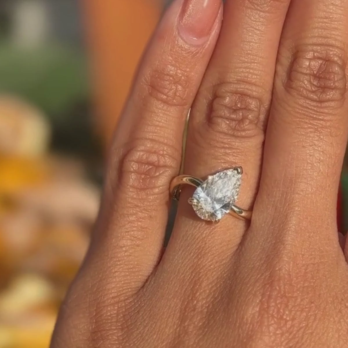 Candid video of pear-cut-solitaire with tilted center stone and pave eternity band shown close-up on hand.