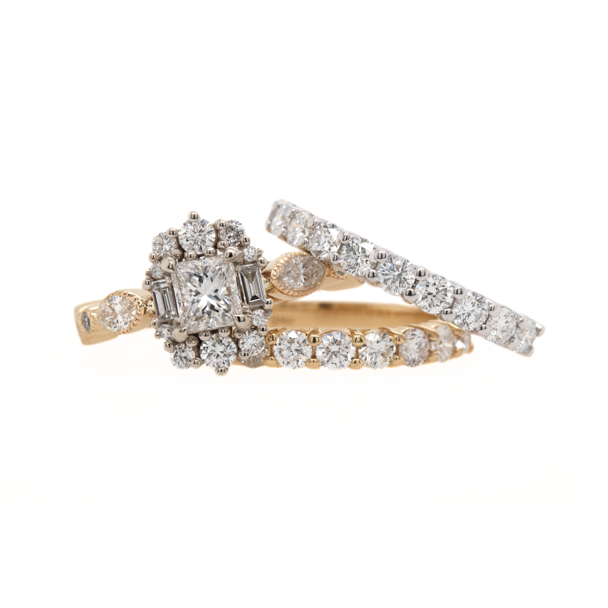 Group shot of geometric diamond cluster ring with yellow and white gold round brilliant prong set eternity rings