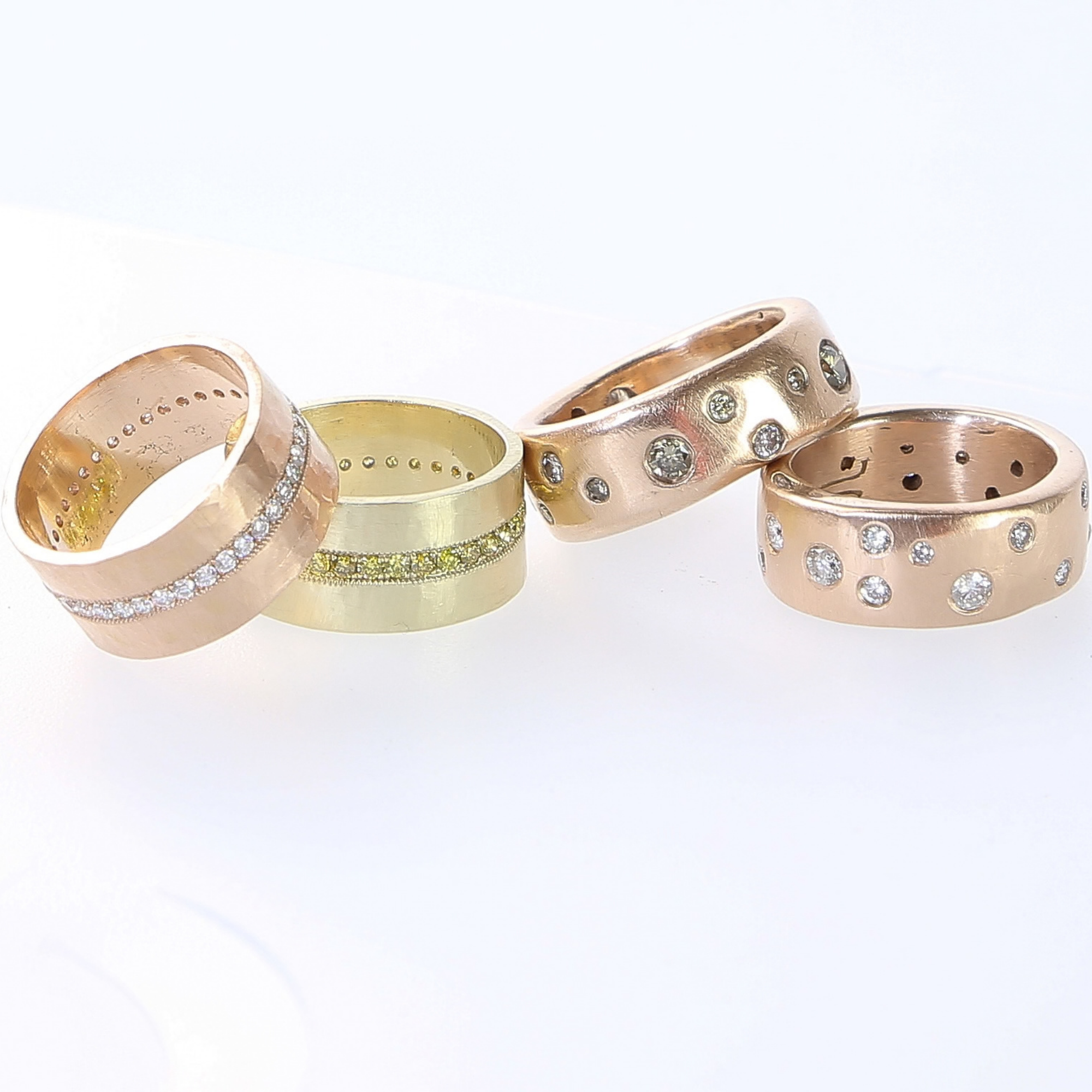 14k gold rani rings with hammered finish and pave set white and yellow diamonds beside two rend rings in rose gold with cognac diamonds and white diamonds on a white background
