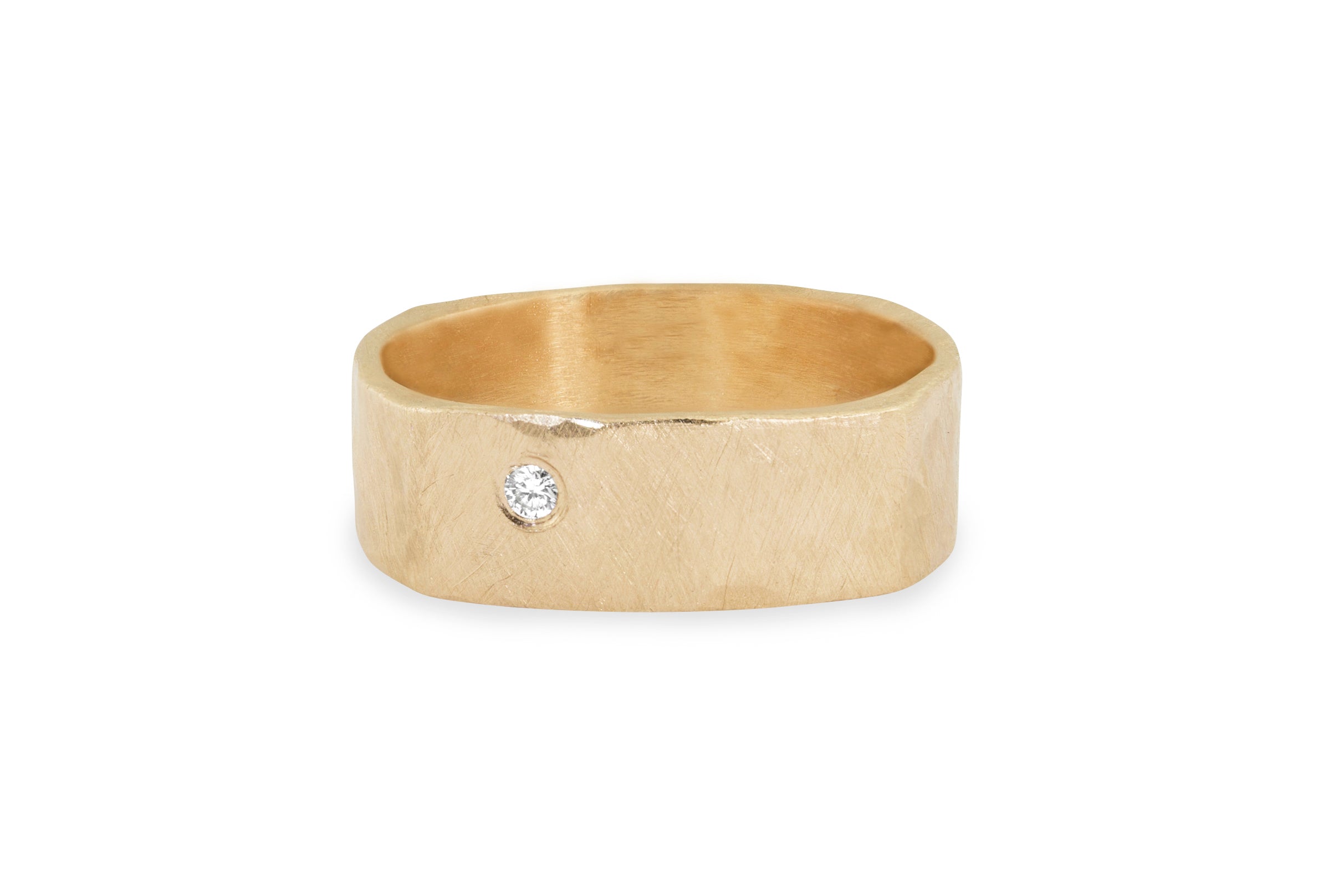 wide band yellow gold ring with a single diamond and satin finish on a white background