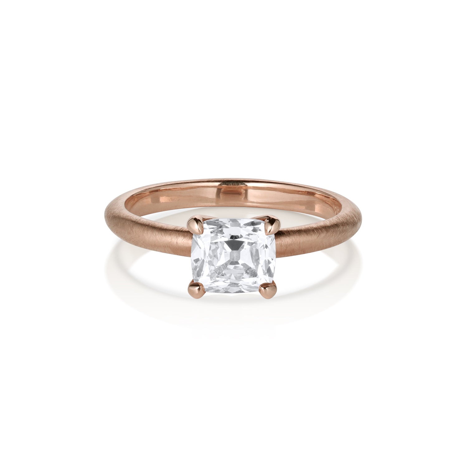 14k Rose gold cushion cut diamond in a prong setting on thin band with satin or shiny finish. Sitting on side on white background.